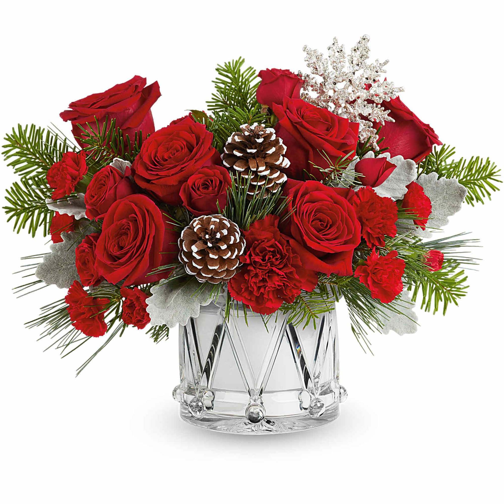 Red roses and carnations in a clear glass vase with pinecones and winter greenery