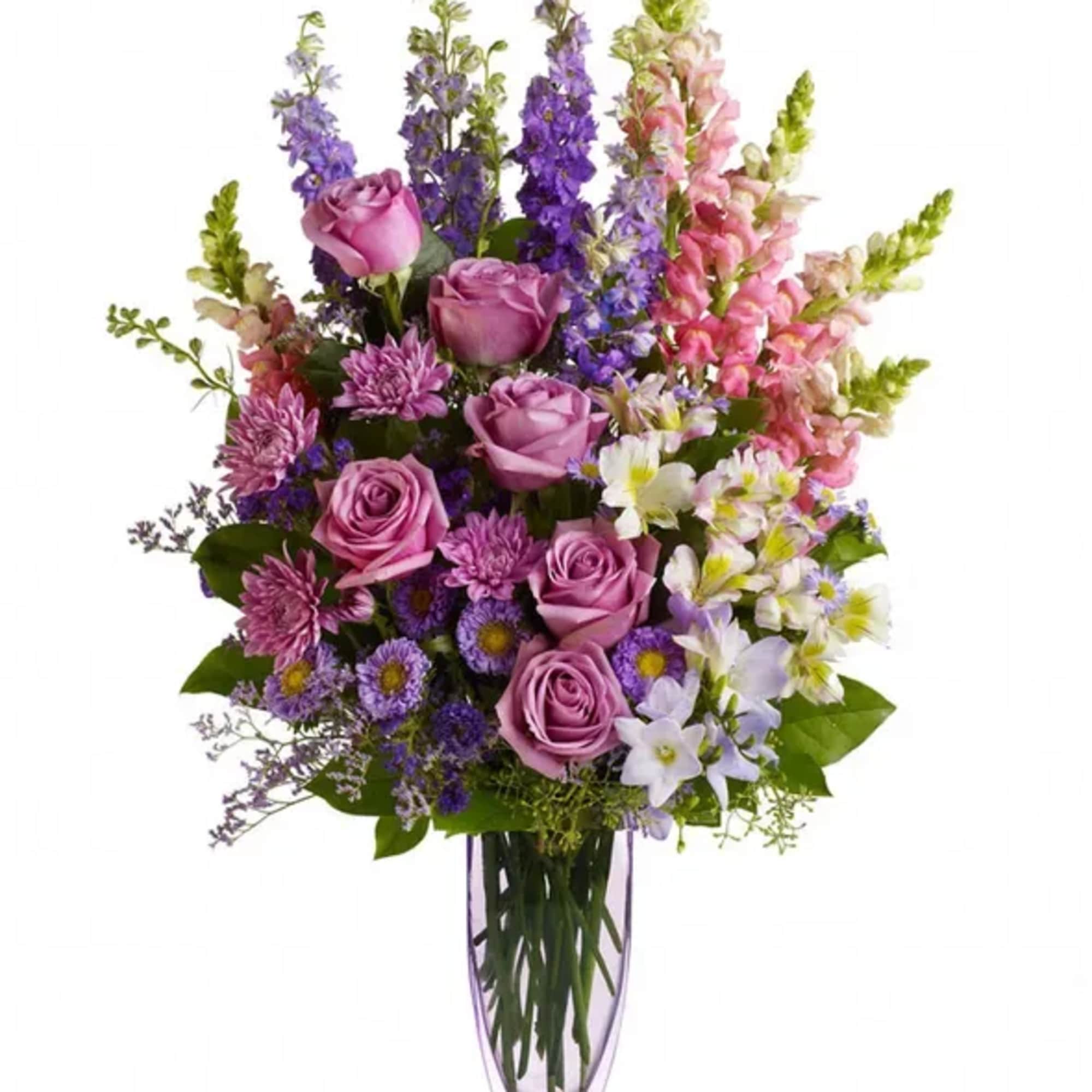 Mixed bouquet of purple roses and tall pink and purple flowers in a glass vase