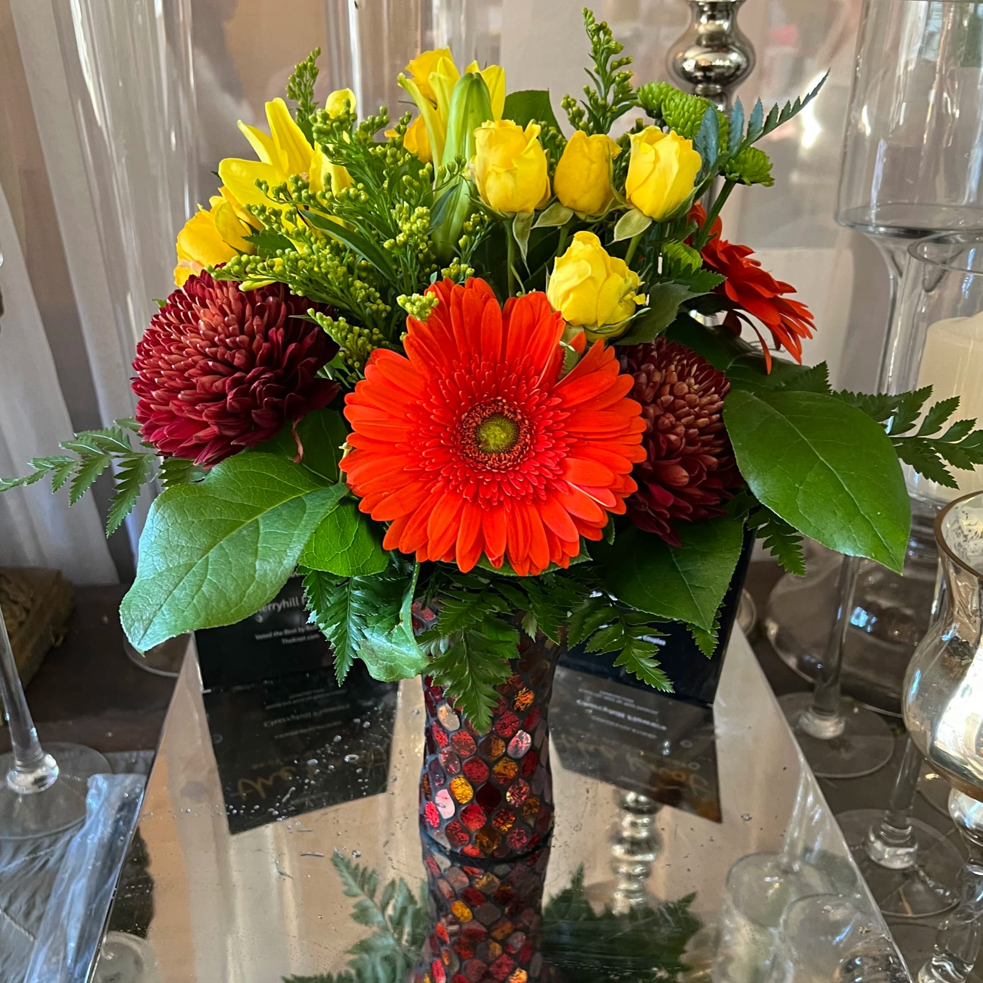 Bright mixed bouquet with gerbera daisies, roses, and chrysanthemums in a mosaic vase