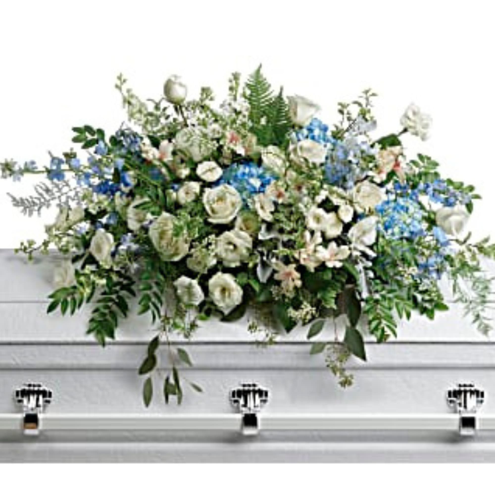 White casket spray with blue flowers and greenery