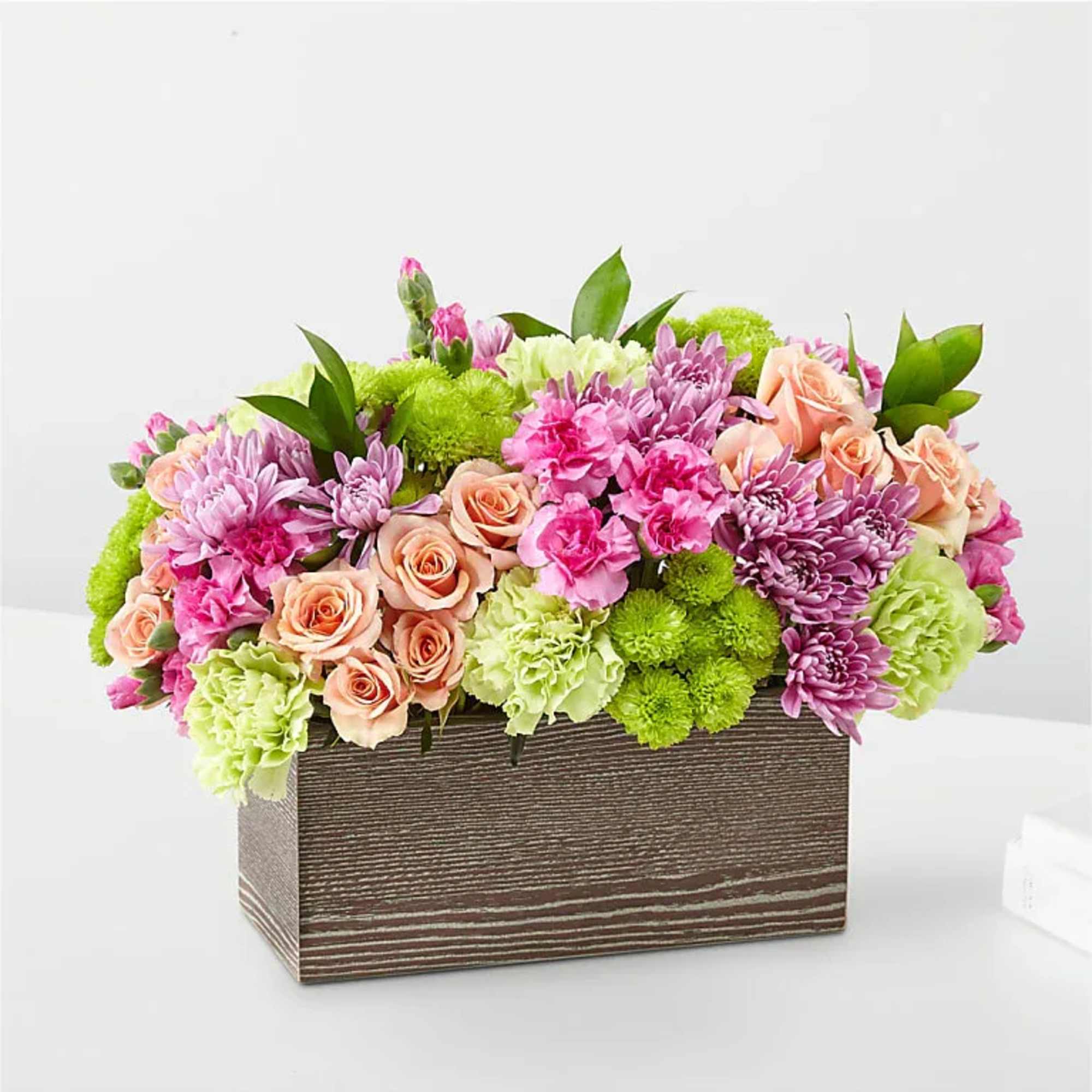Mixed pink, peach, and green flowers arranged in a rectangular wooden box