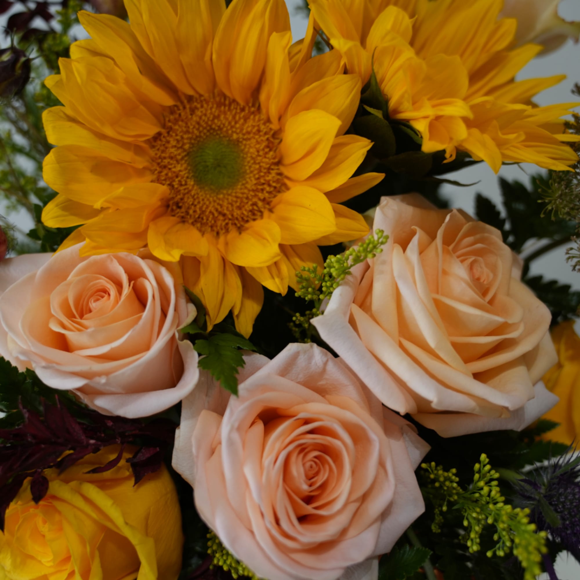 Peach roses with bright yellow sunflowers in a bouquet