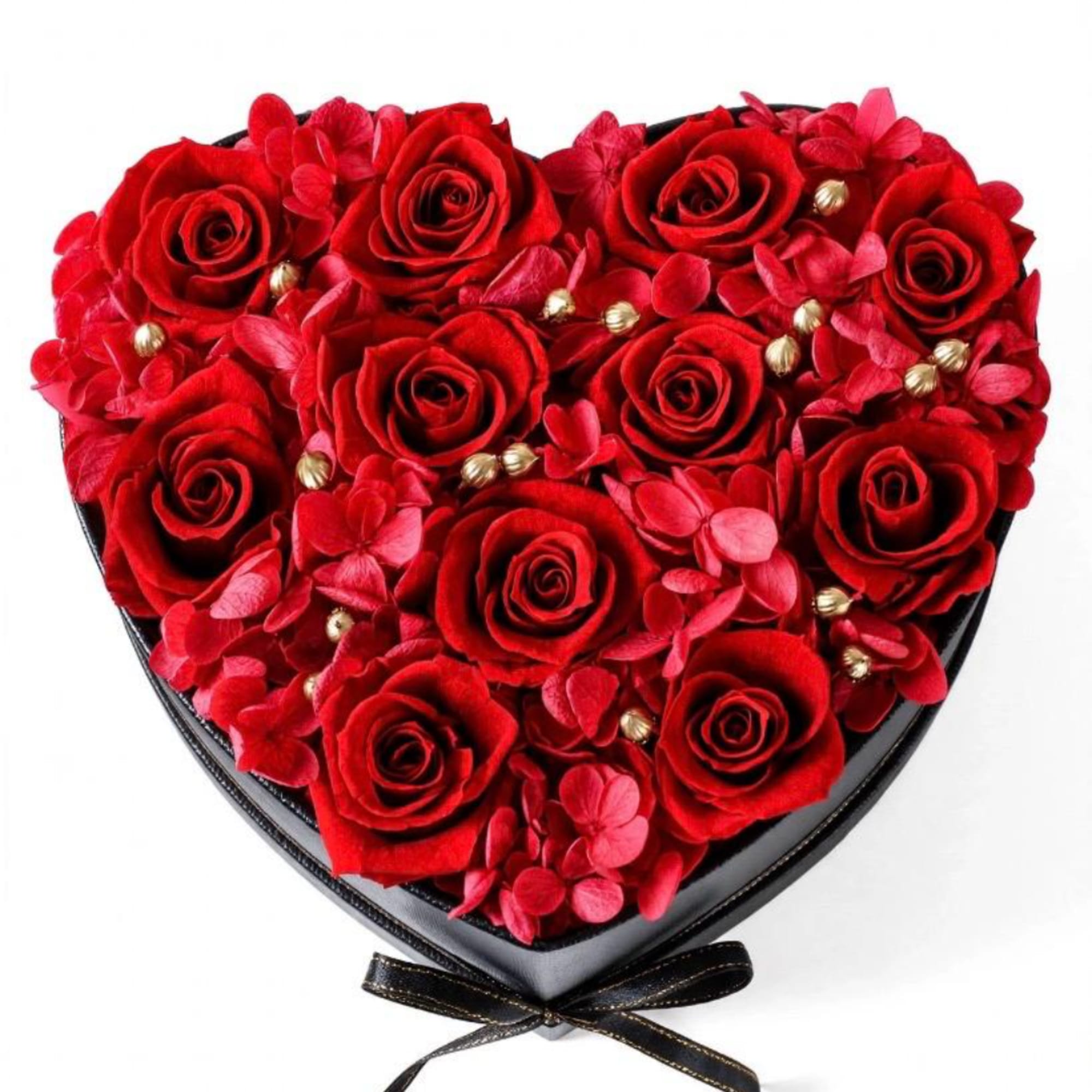 Heart-shaped box filled with red roses and pink petals, tied with a black ribbon