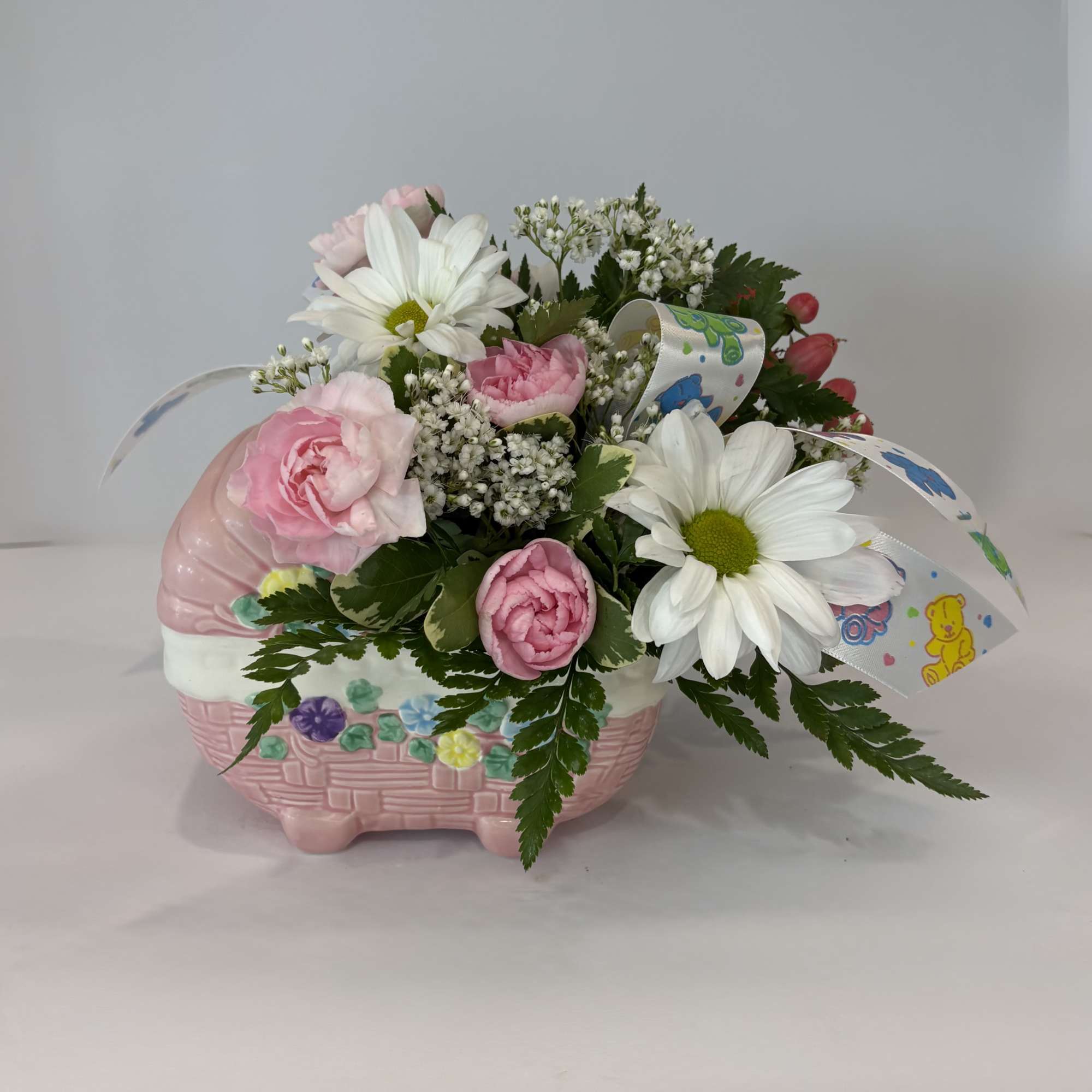 Pink and white flowers arranged in a pink basket-shaped container