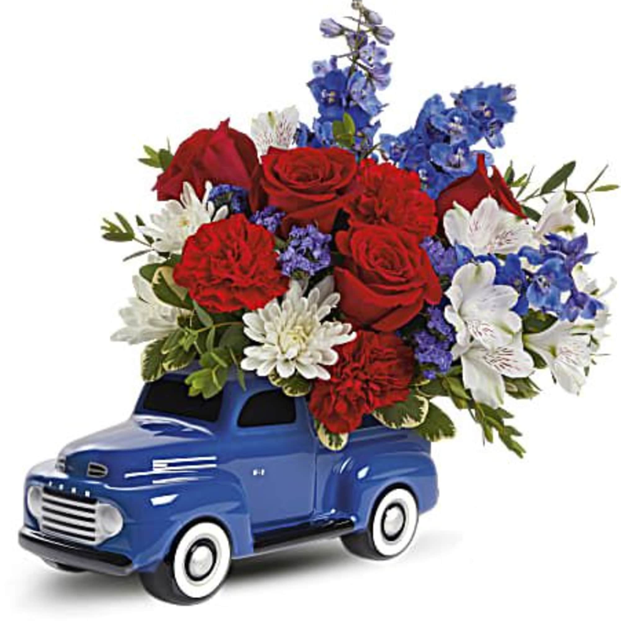 Blue toy truck filled with red, white, and blue flowers