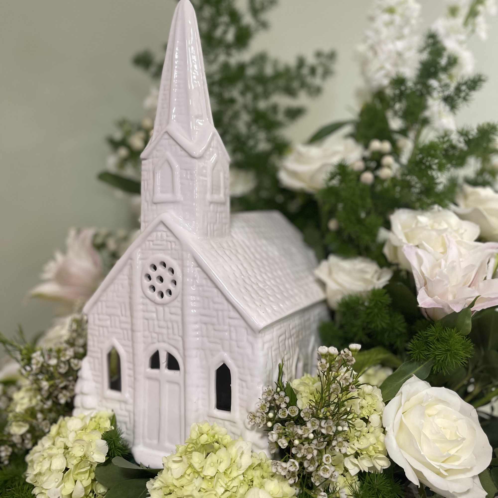 White ceramic church surrounded by white and pale green flowers