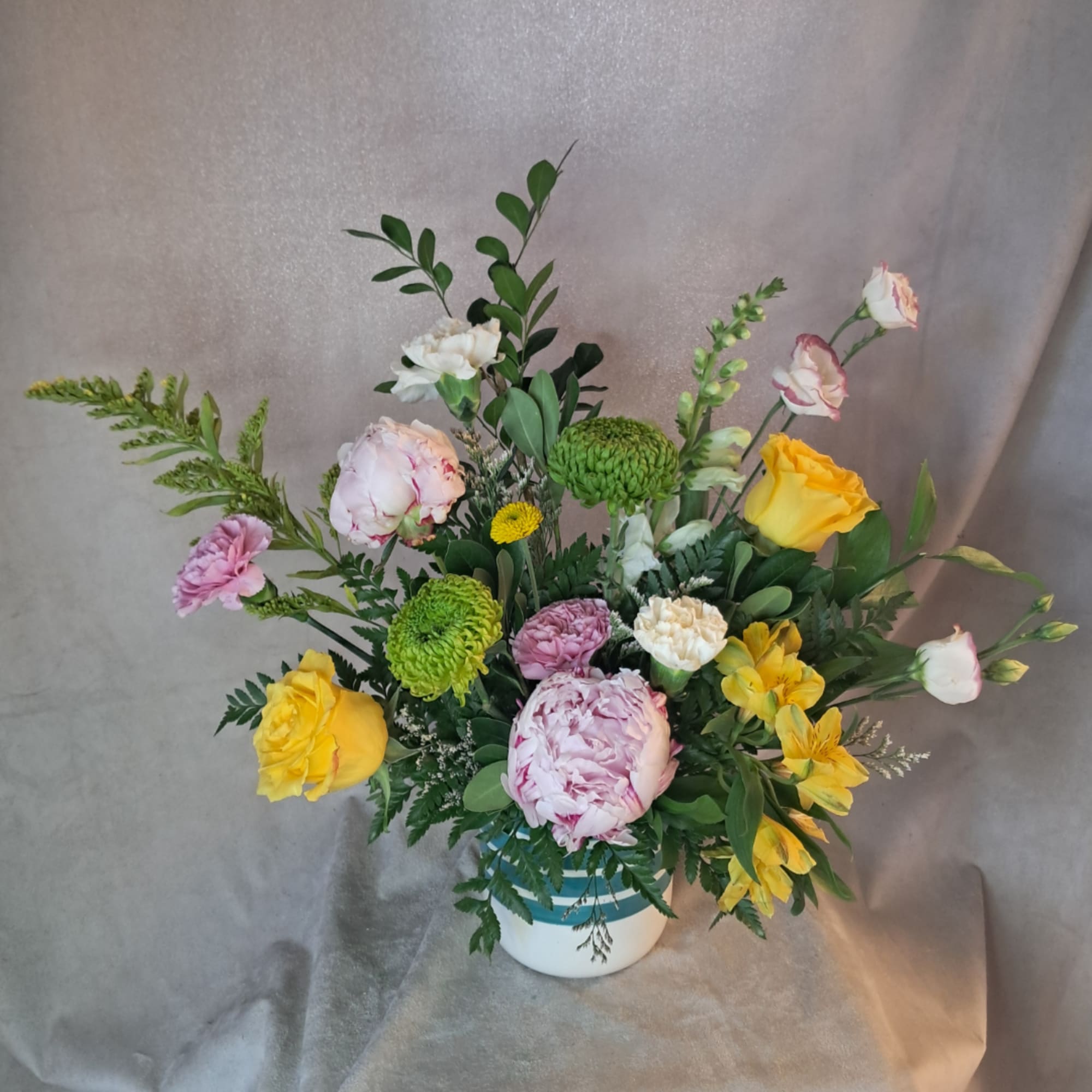 Mixed floral arrangement in a white vase with yellow and pink blooms