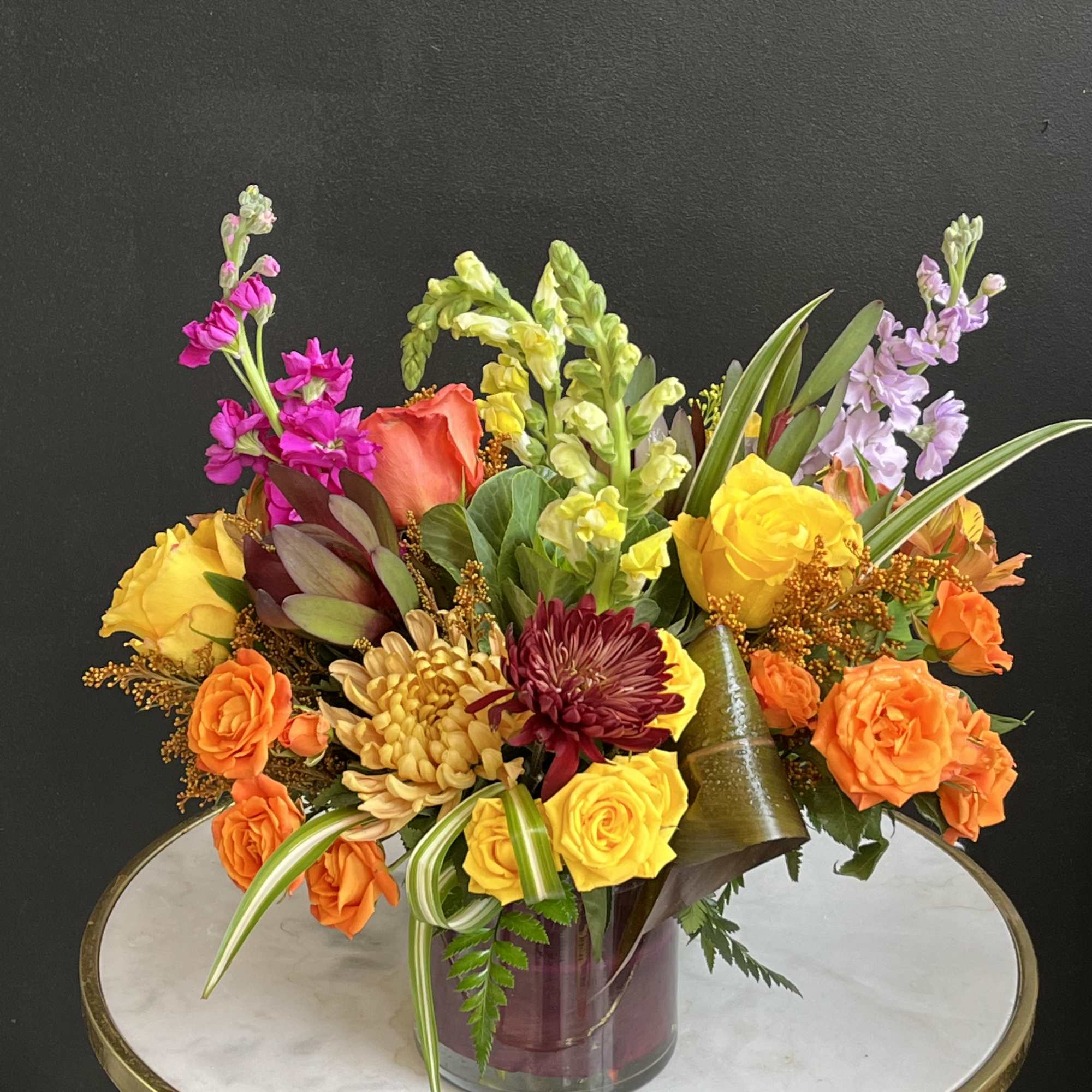 Colorful mixed bouquet in a glass vase with roses and snapdragons