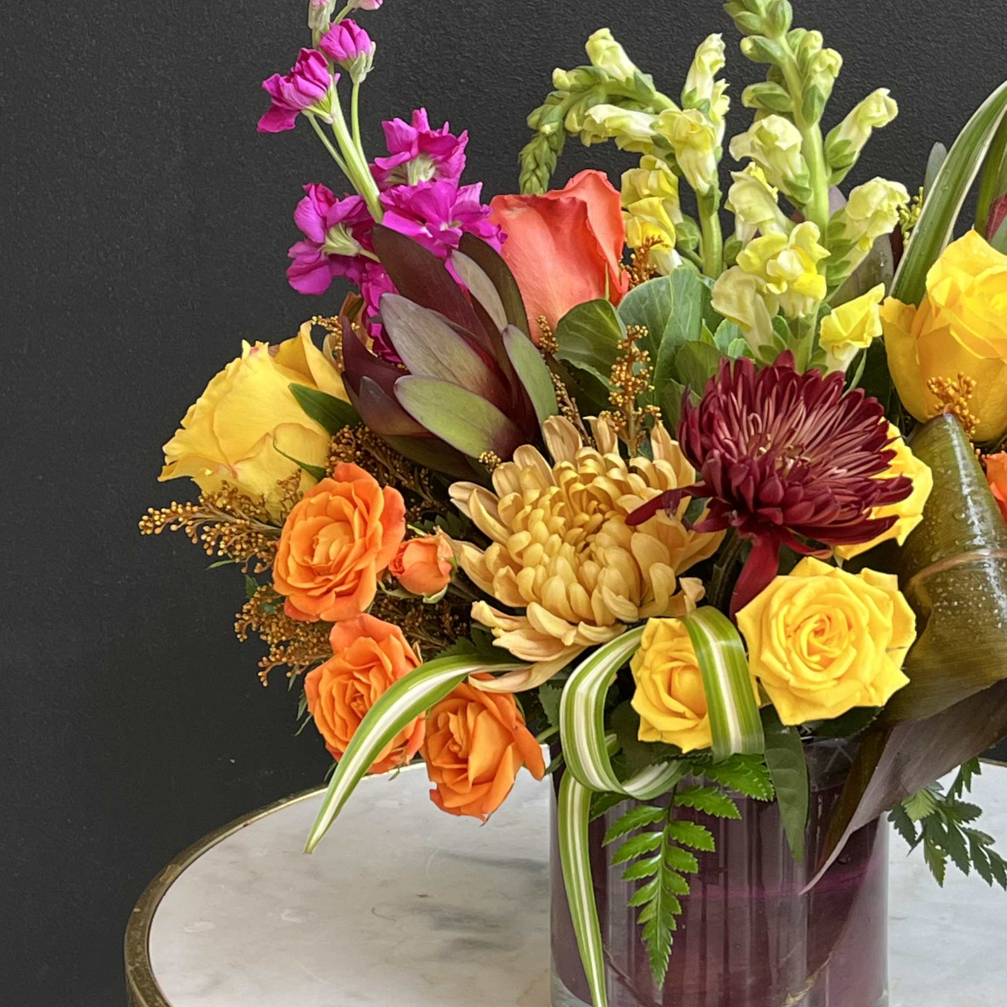 Colorful mixed bouquet in a clear glass vase with roses and chrysanthemums