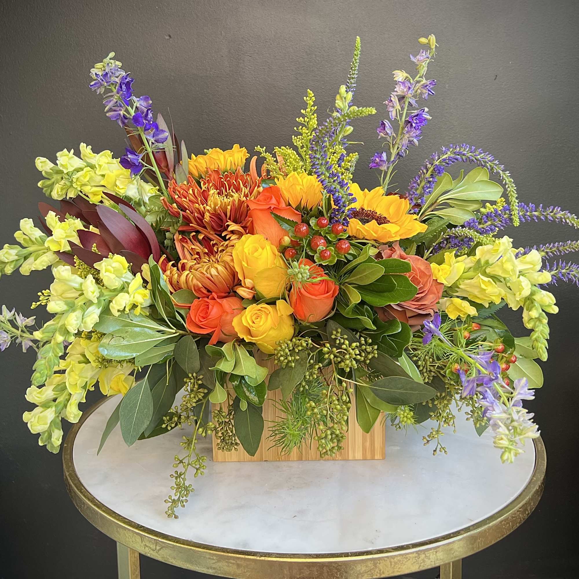Colorful mixed flower arrangement in a wooden box on a round table