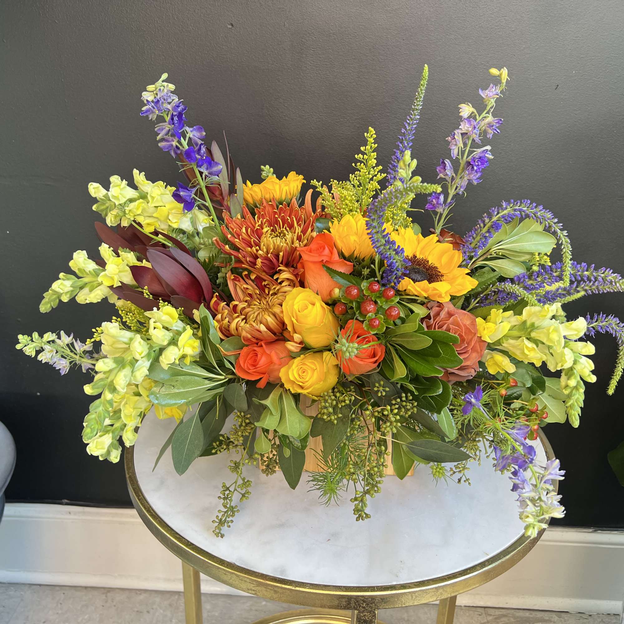 Mixed bouquet of orange, yellow, purple, and green flowers in a vase