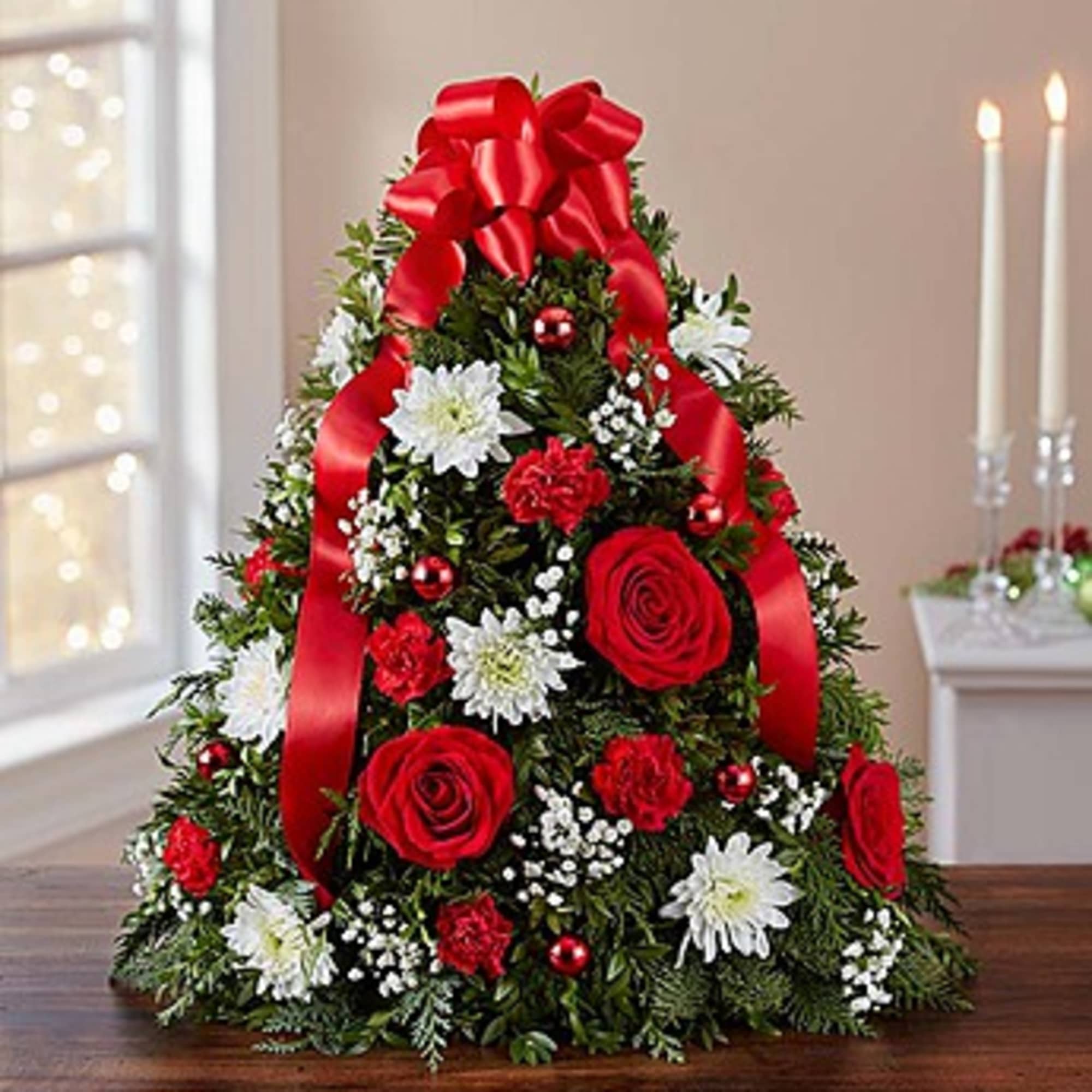 Christmas tree-shaped floral arrangement with red ribbon and red and white flowers