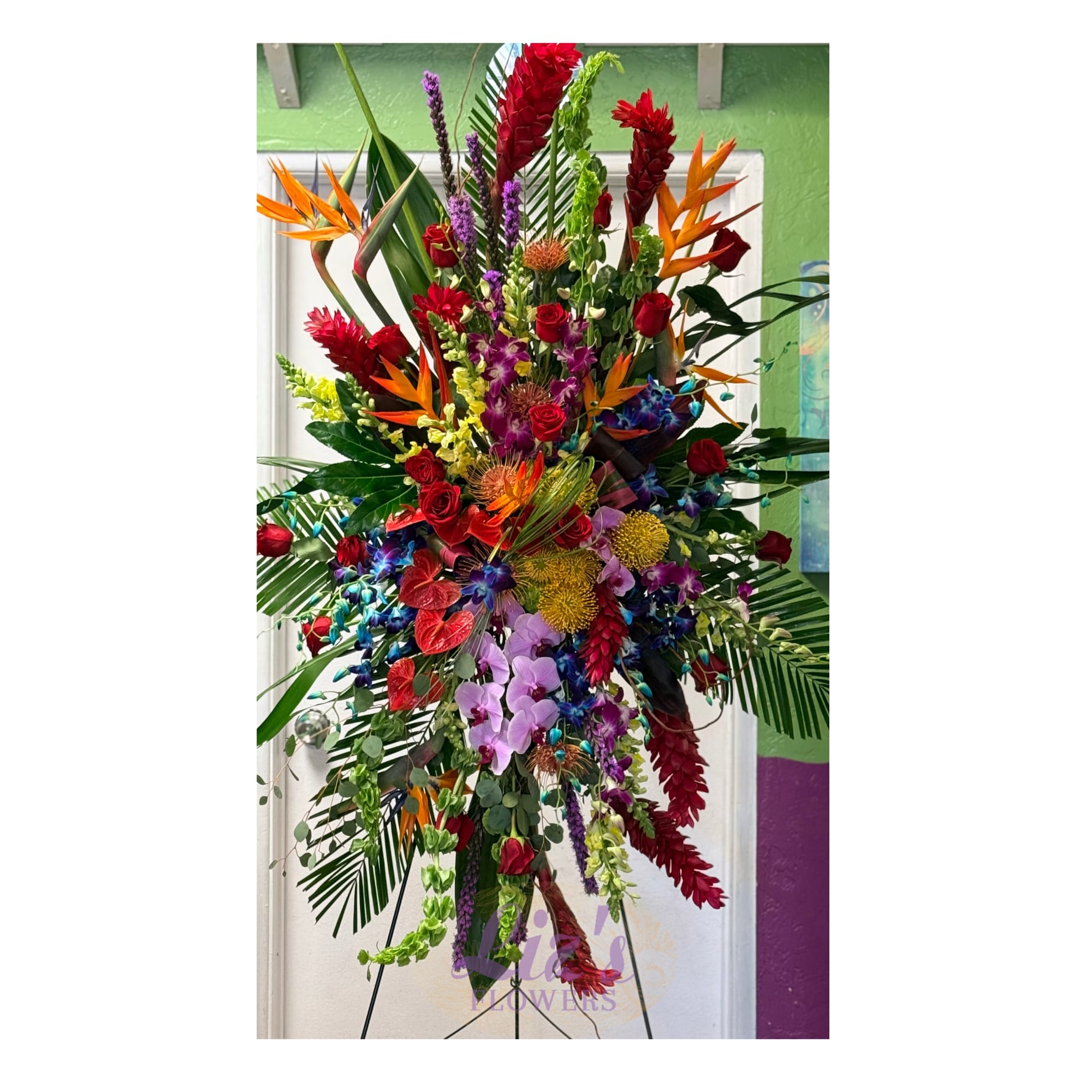 Tall, multicolored tropical standing spray with roses, orchids, birds of paradise on an easel