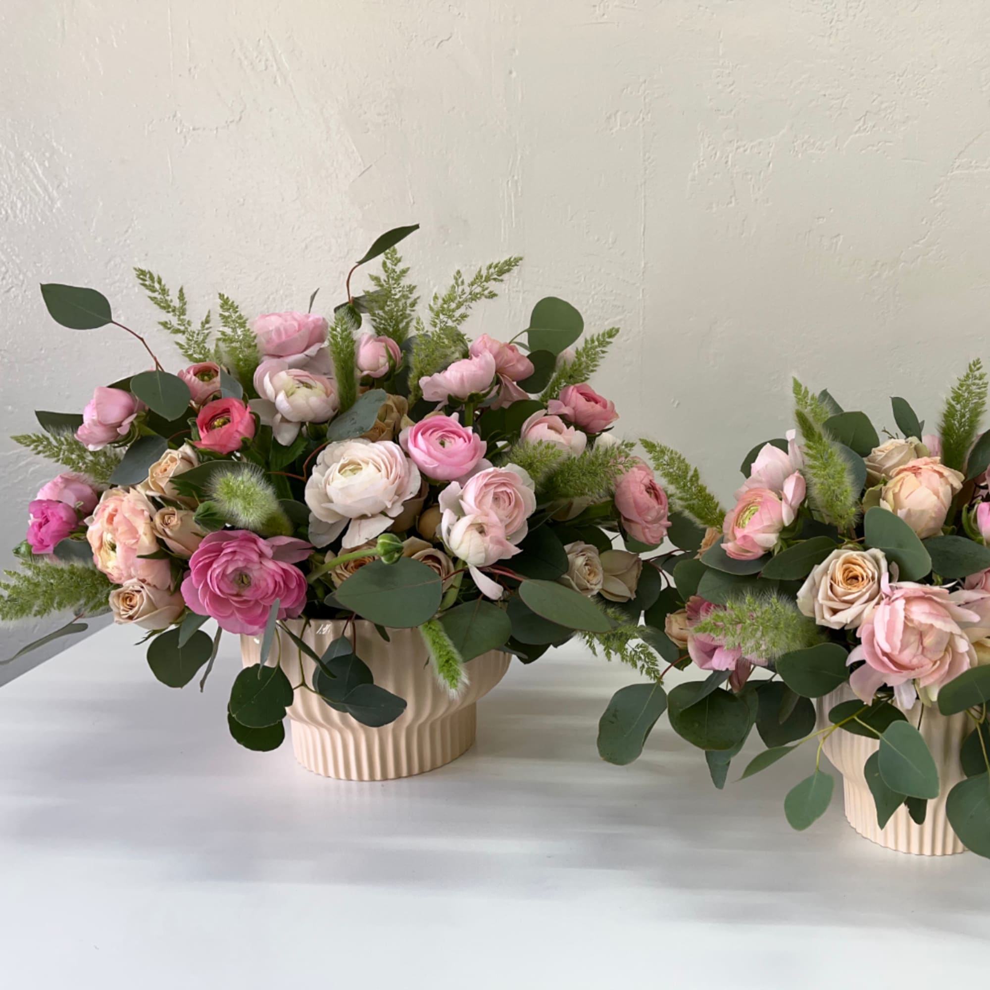 Pink and white flowers arranged in cream ribbed vases