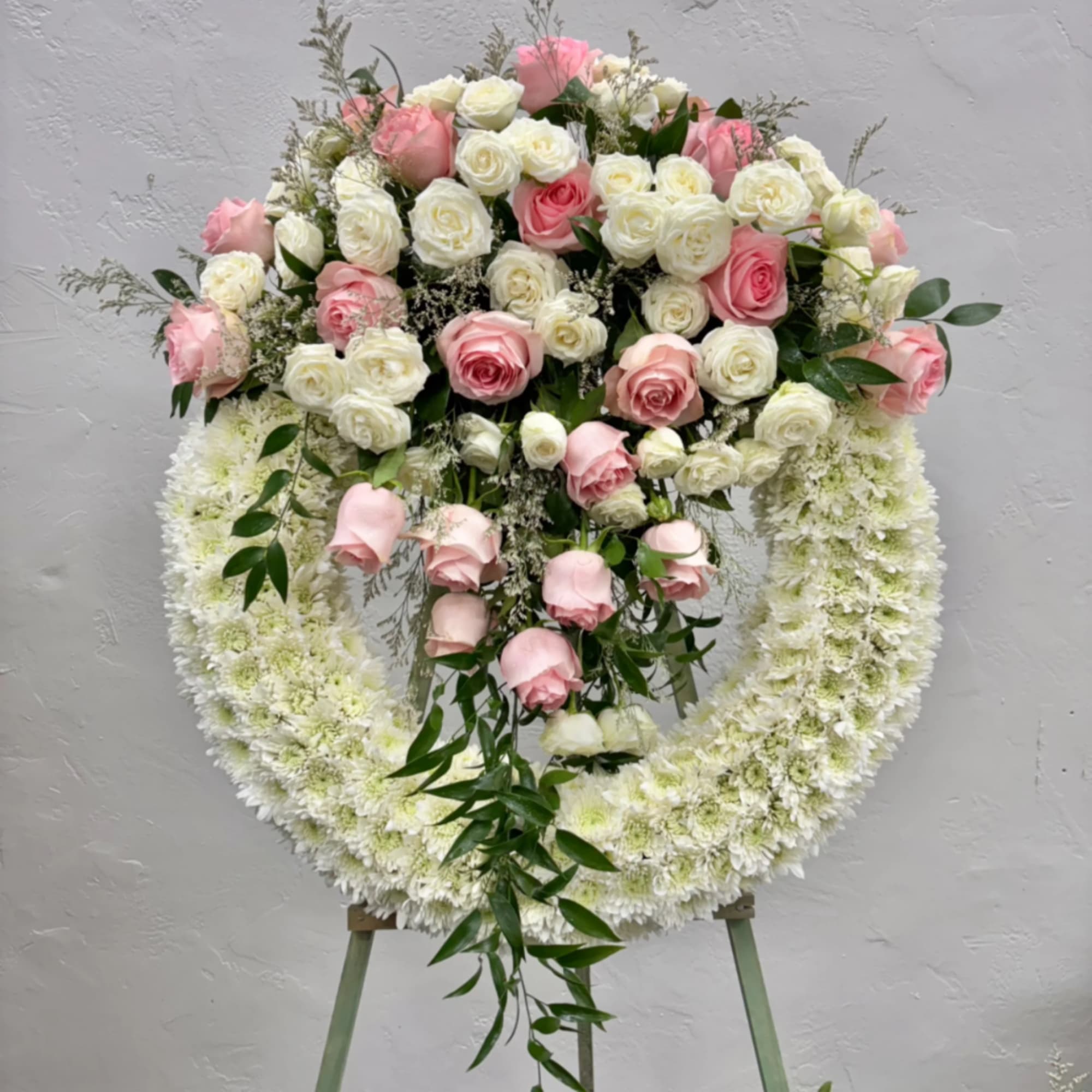 Pink and white rose funeral wreath on an easel