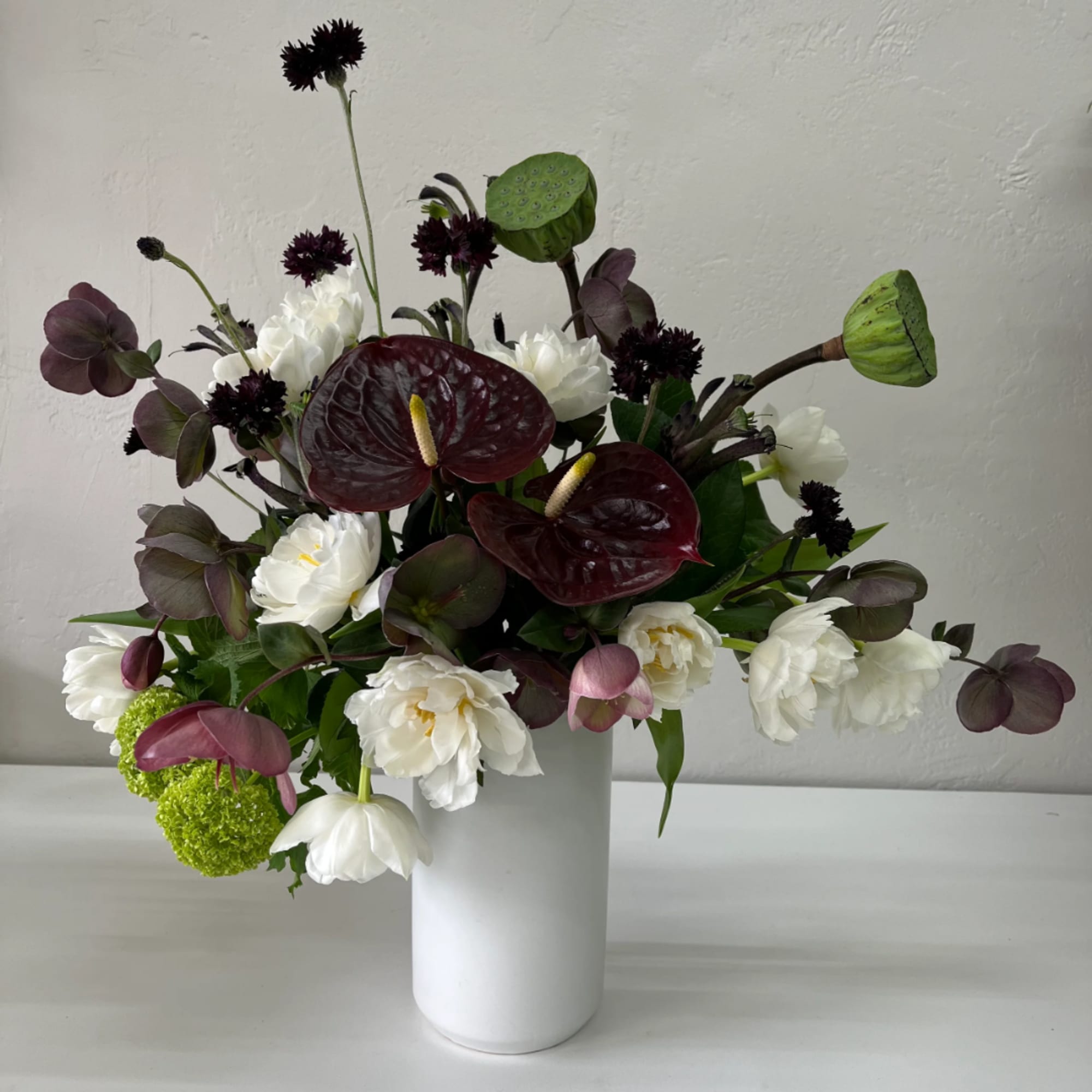 White and burgundy floral arrangement in a white vase