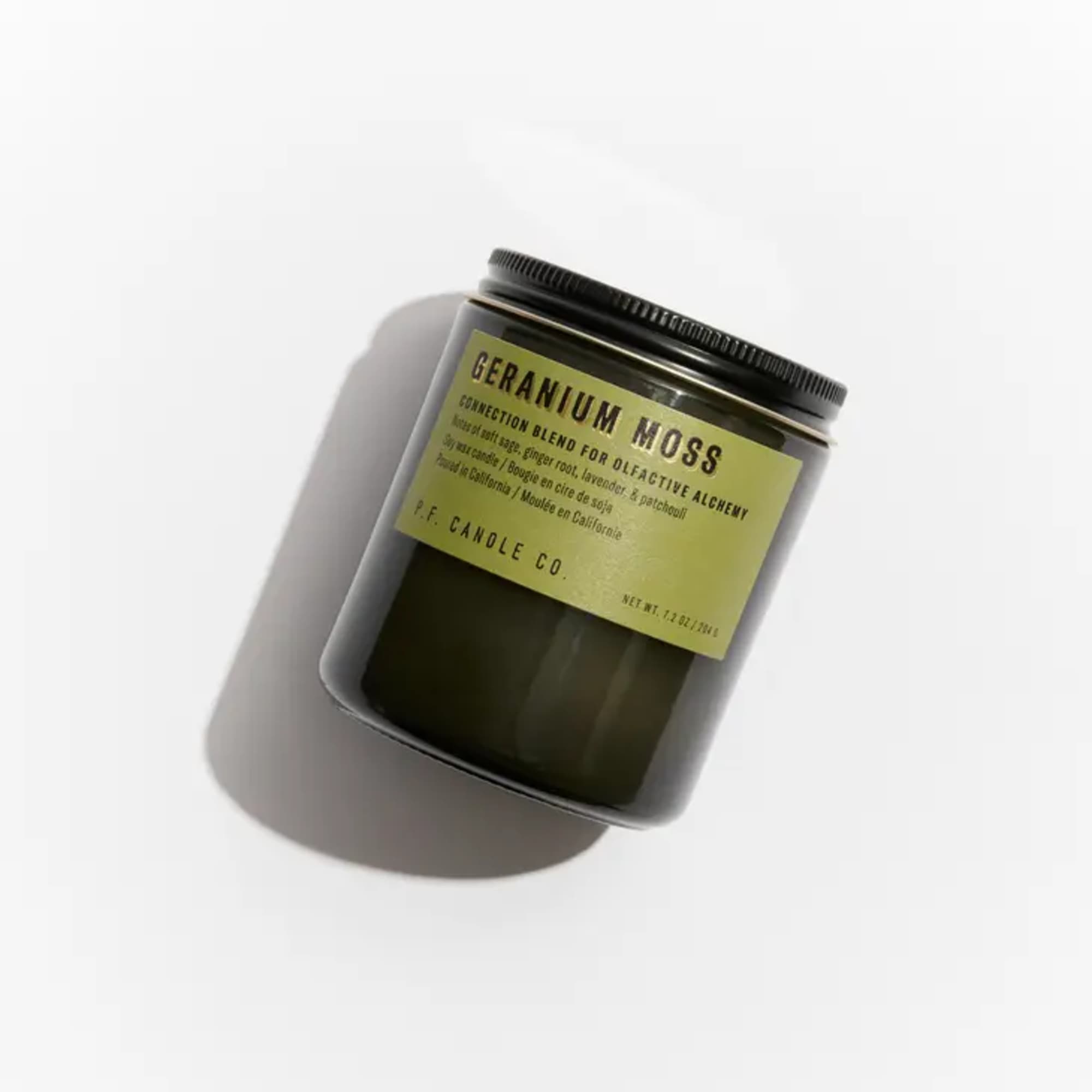 Dark glass candle jar with a black lid and green label