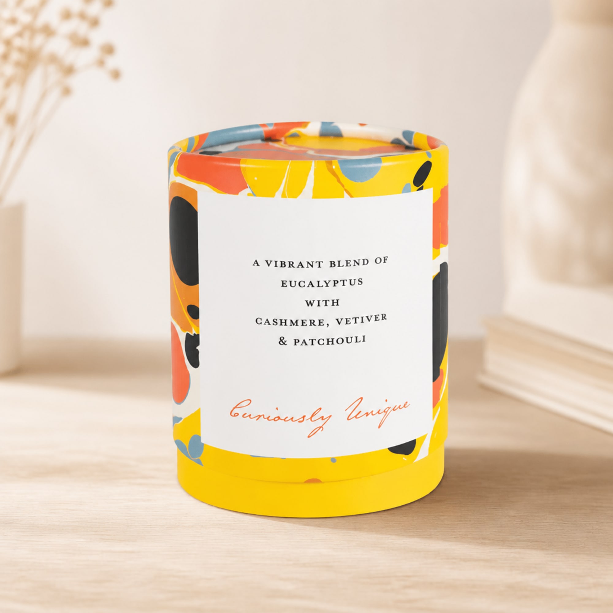 Colorful scented candle in a patterned glass jar on a table