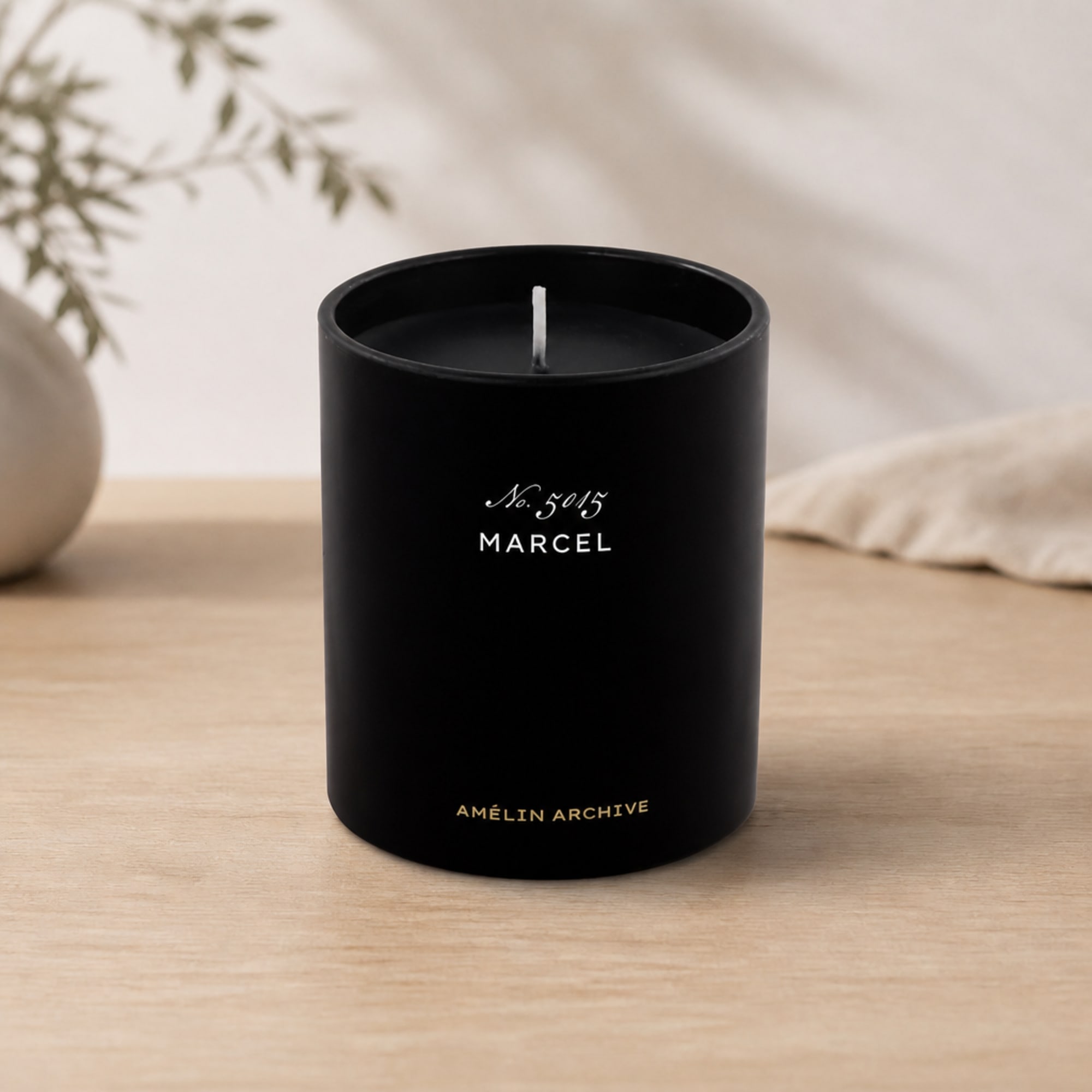 Black candle in a cylindrical container on a wooden surface