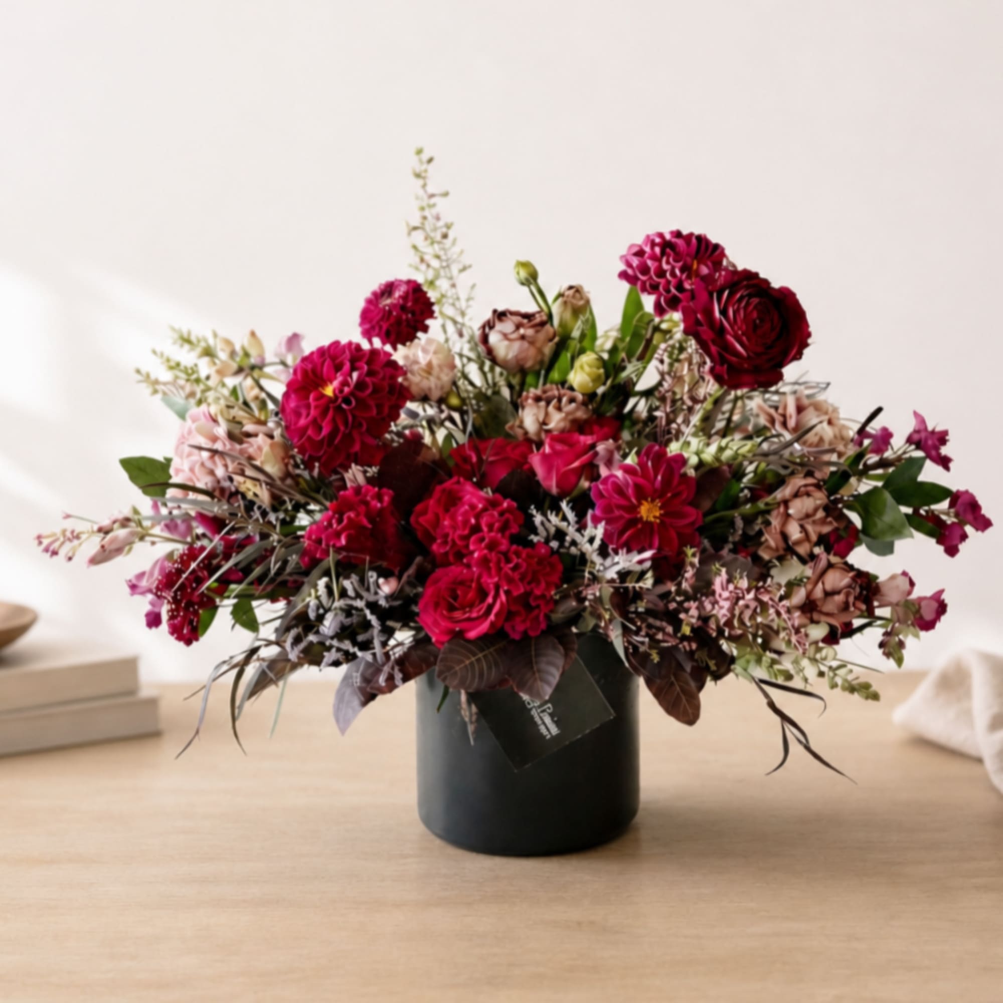 Mixed pink and burgundy flowers arranged in a black vase