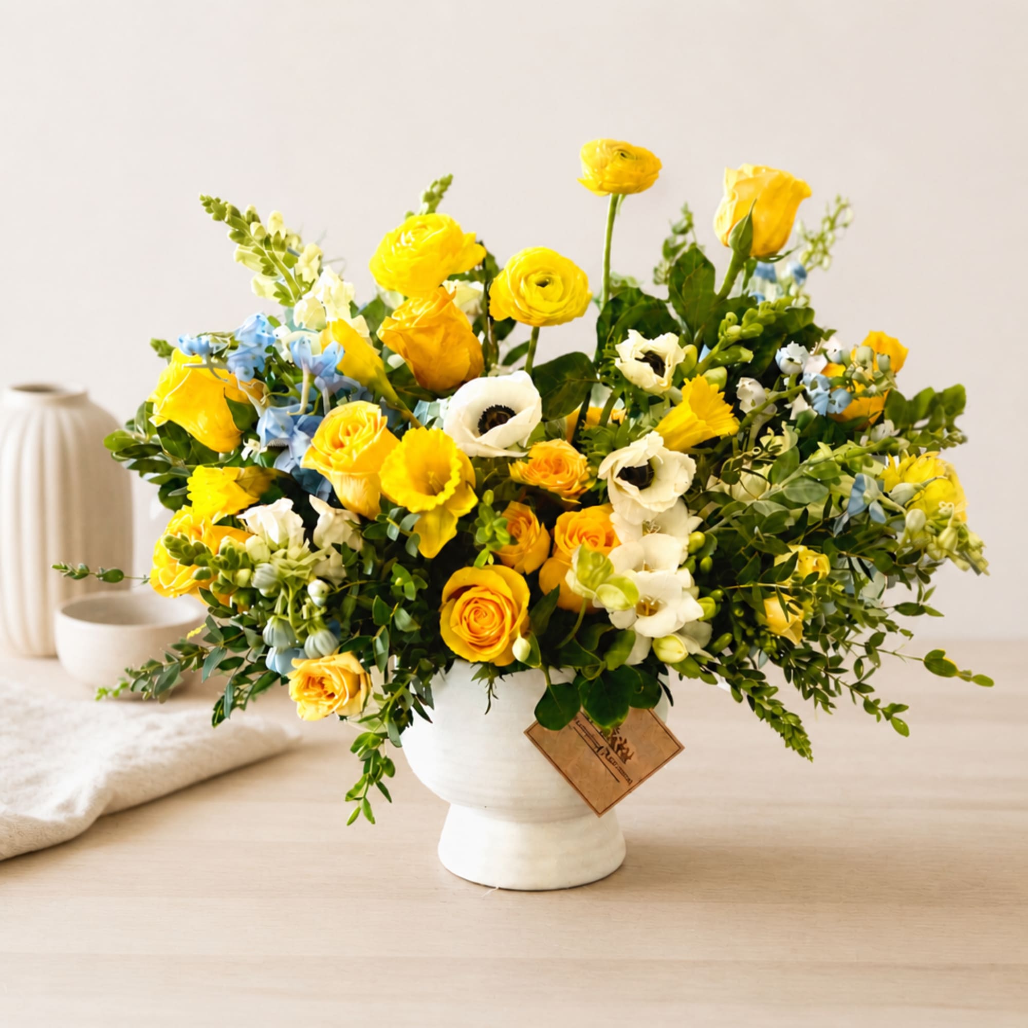 Yellow and white mixed flower arrangement in a white vase