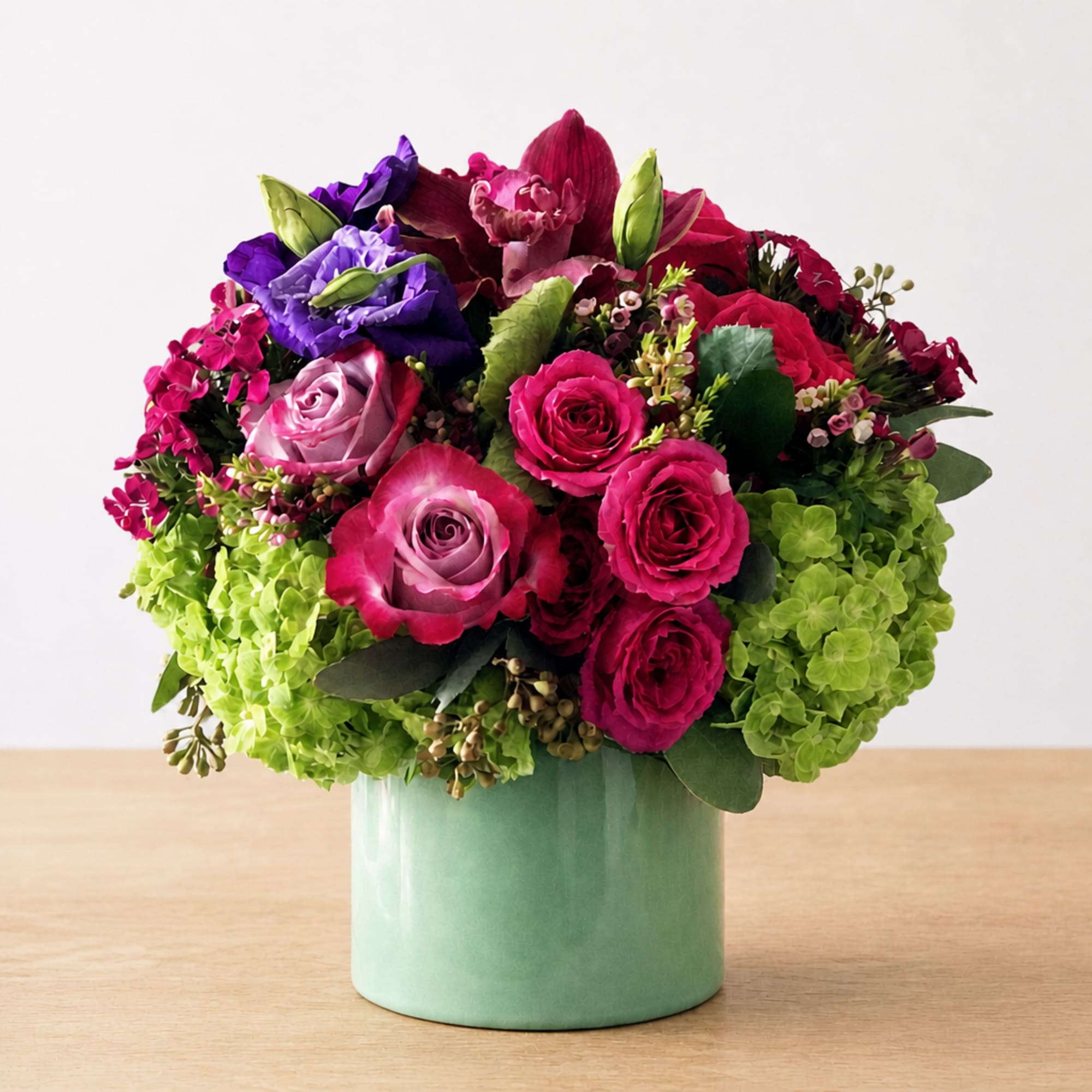 Colorful bouquet of roses and hydrangeas in a mint green vase