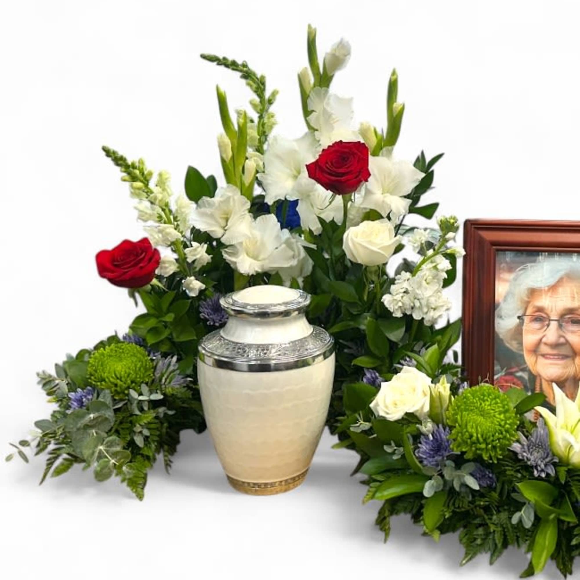 Sympathy floral arrangement with red and white roses beside a memorial urn