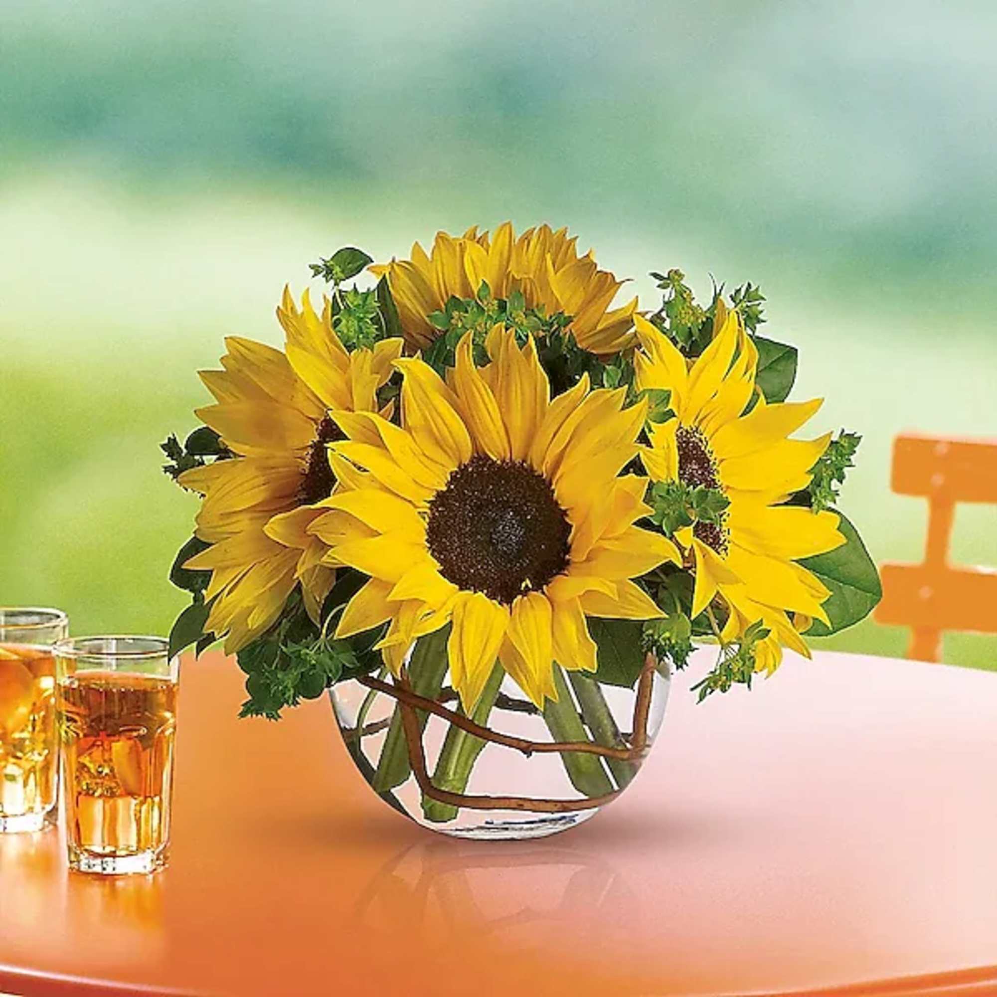 Sunflower bouquet in a clear glass vase on an orange table