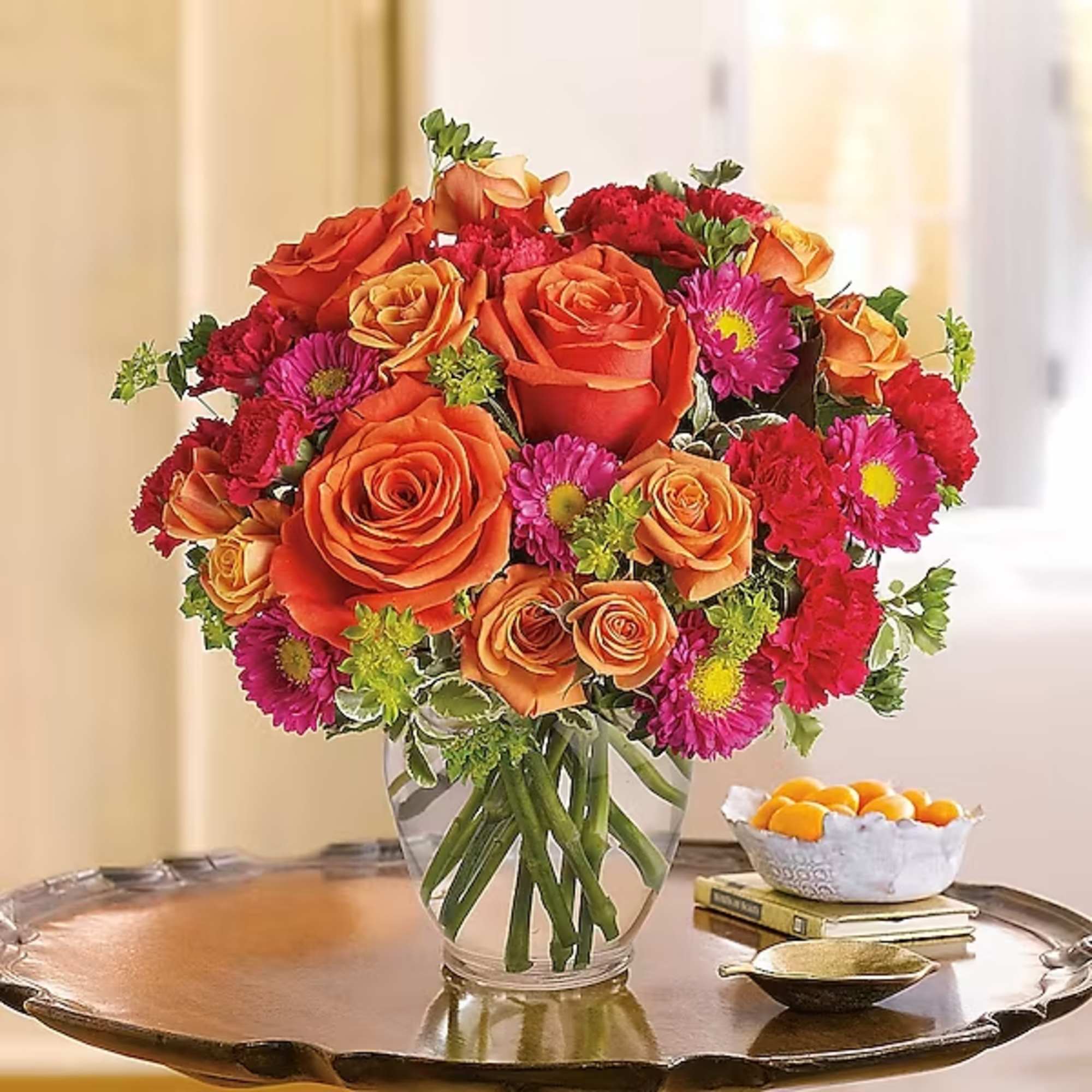 Bouquet of orange roses and pink daisies in a glass vase