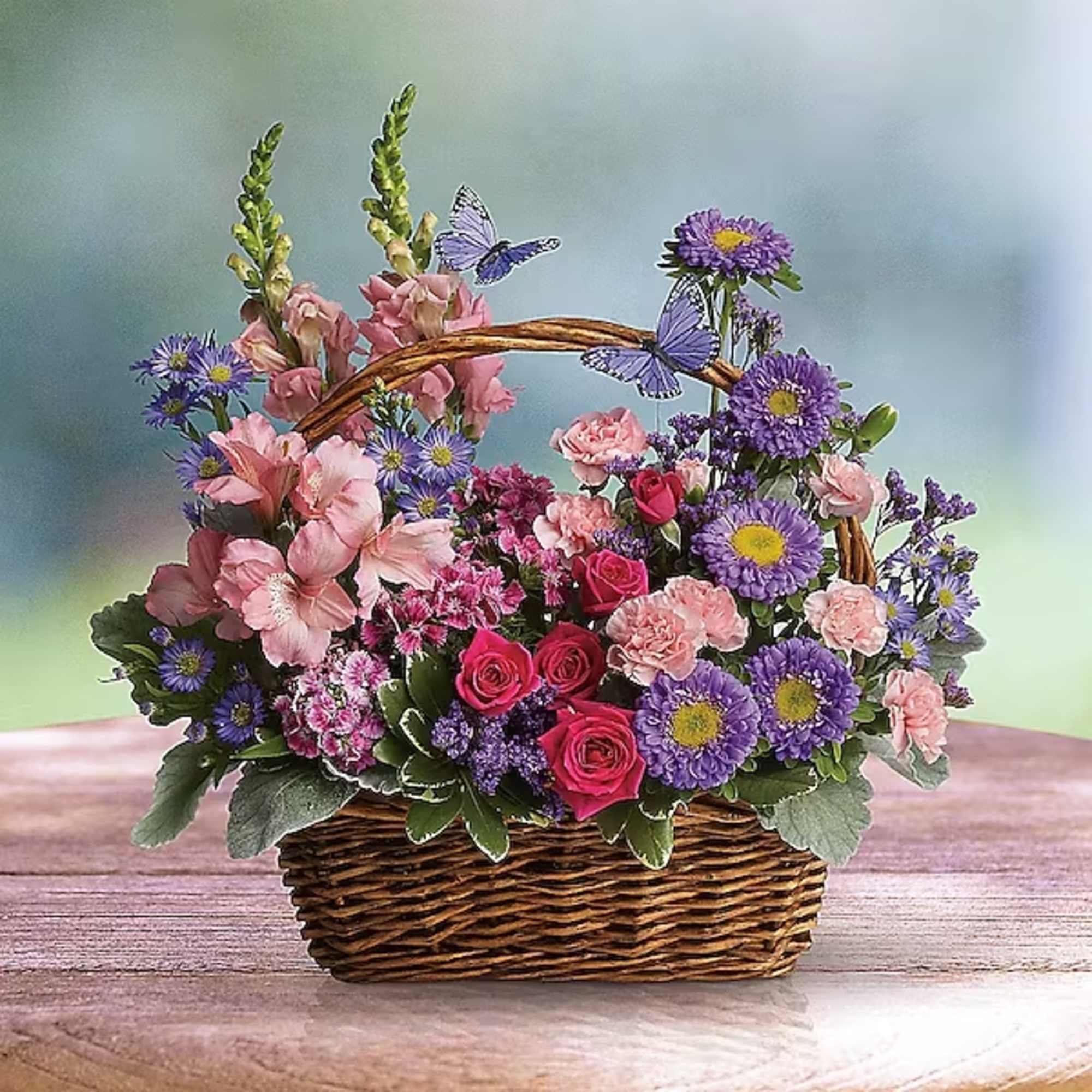 Basket arrangement of pink and purple flowers with butterfly accents