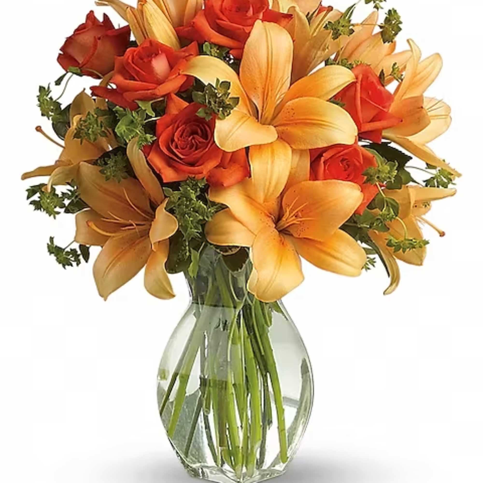 Orange roses and lilies in a clear glass vase