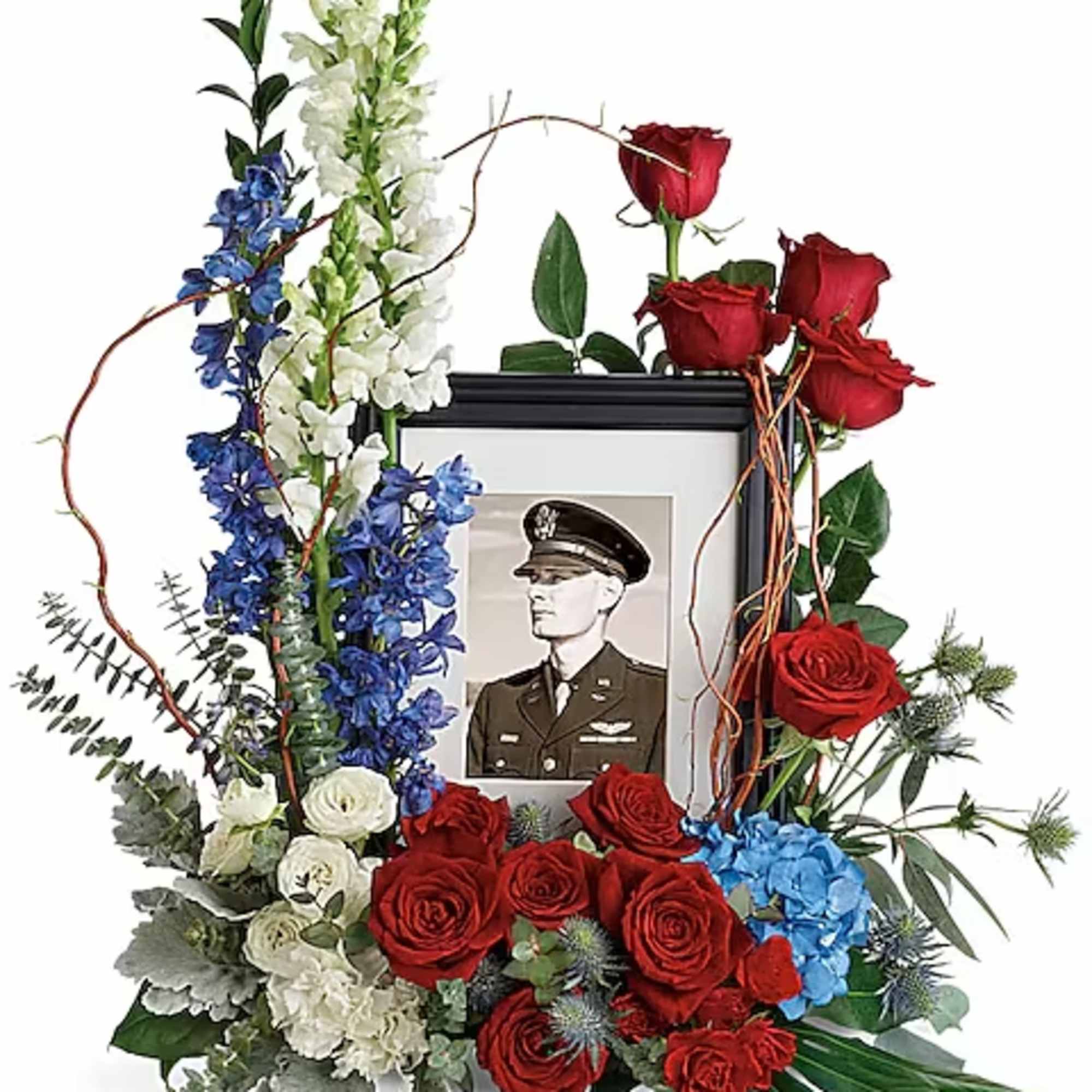 Floral tribute around a framed portrait with red roses and blue-white flowers