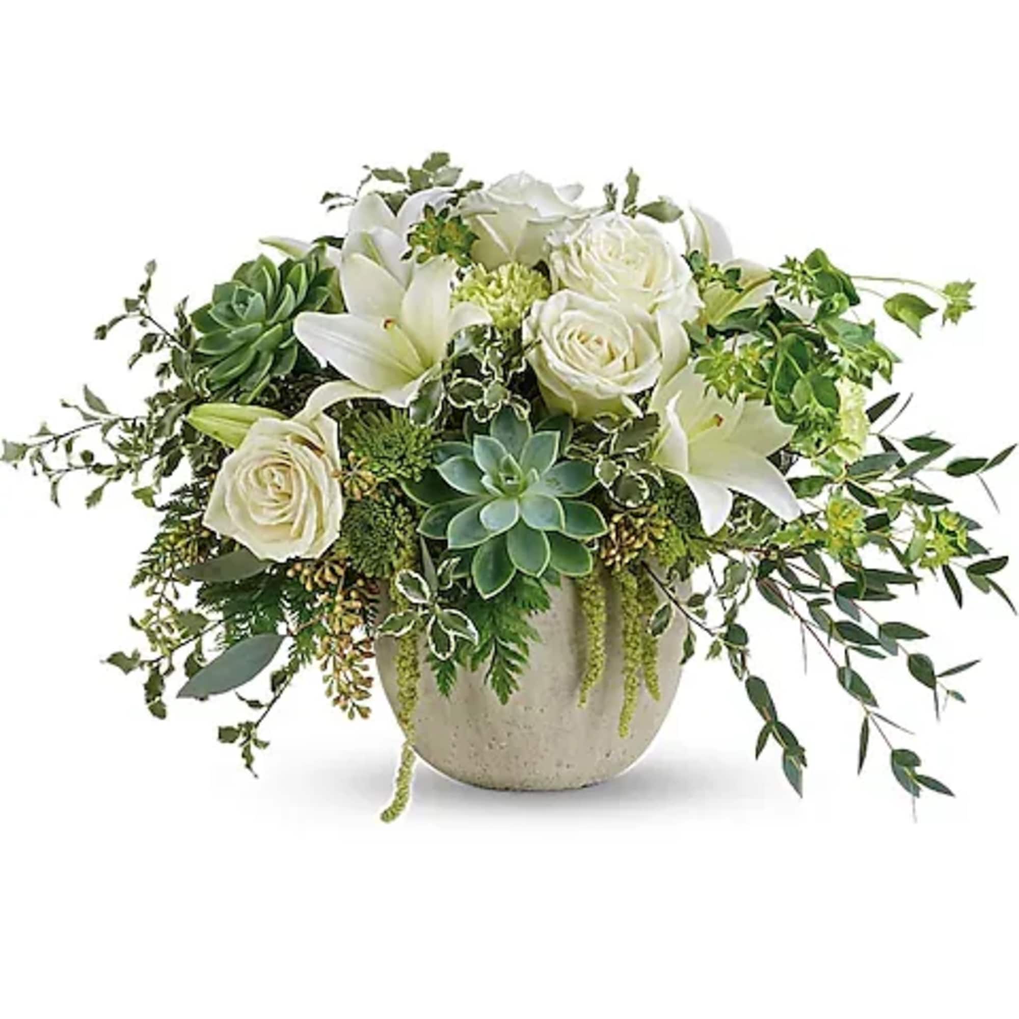 White roses and lilies in a round ceramic vase with trailing greenery