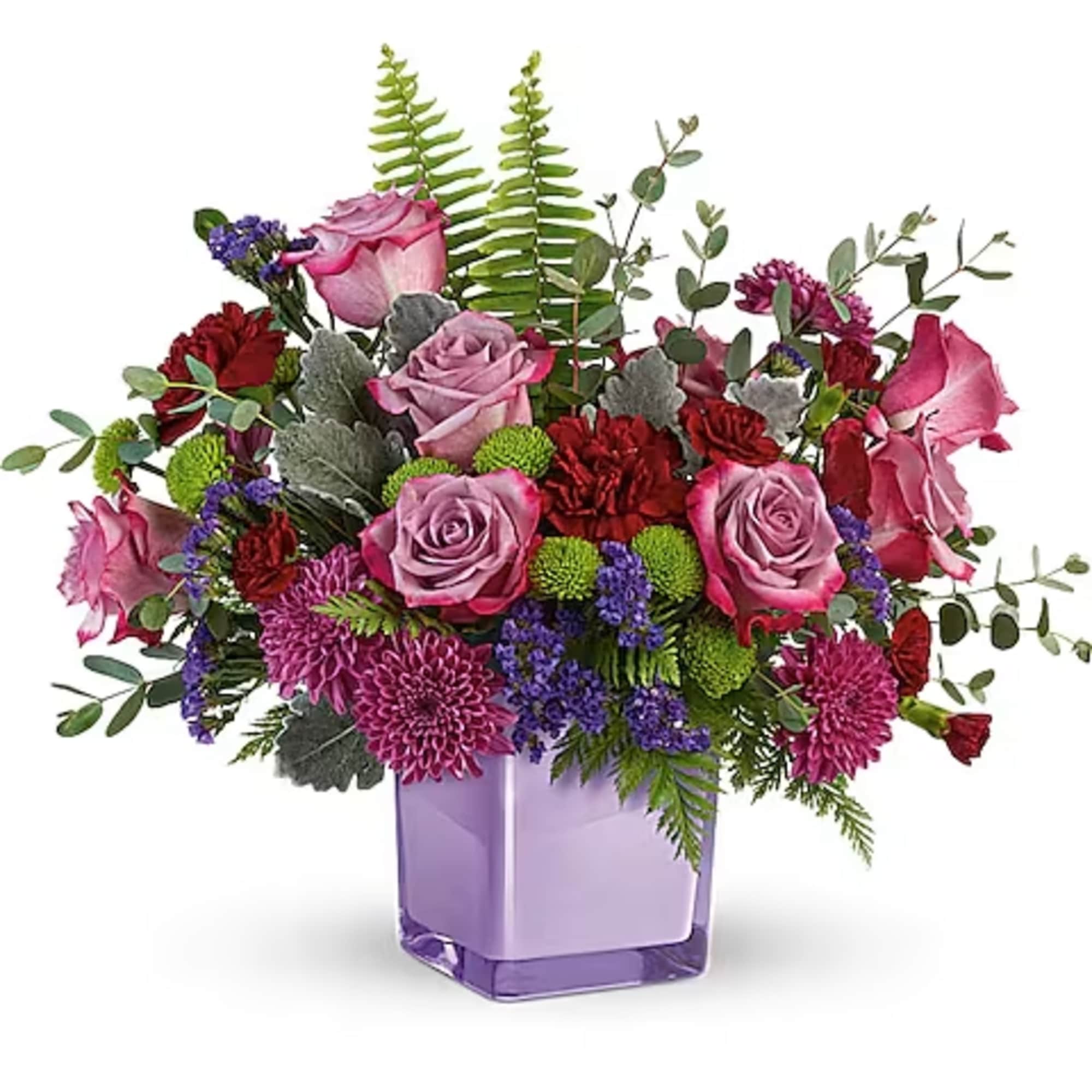 Mixed bouquet of pink roses, red blooms, and purple flowers in a lavender vase