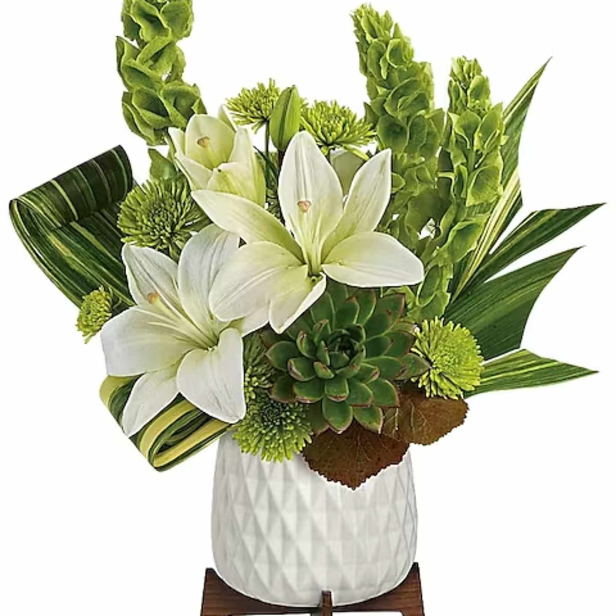 White lilies and green blooms in a white vase with tropical leaves
