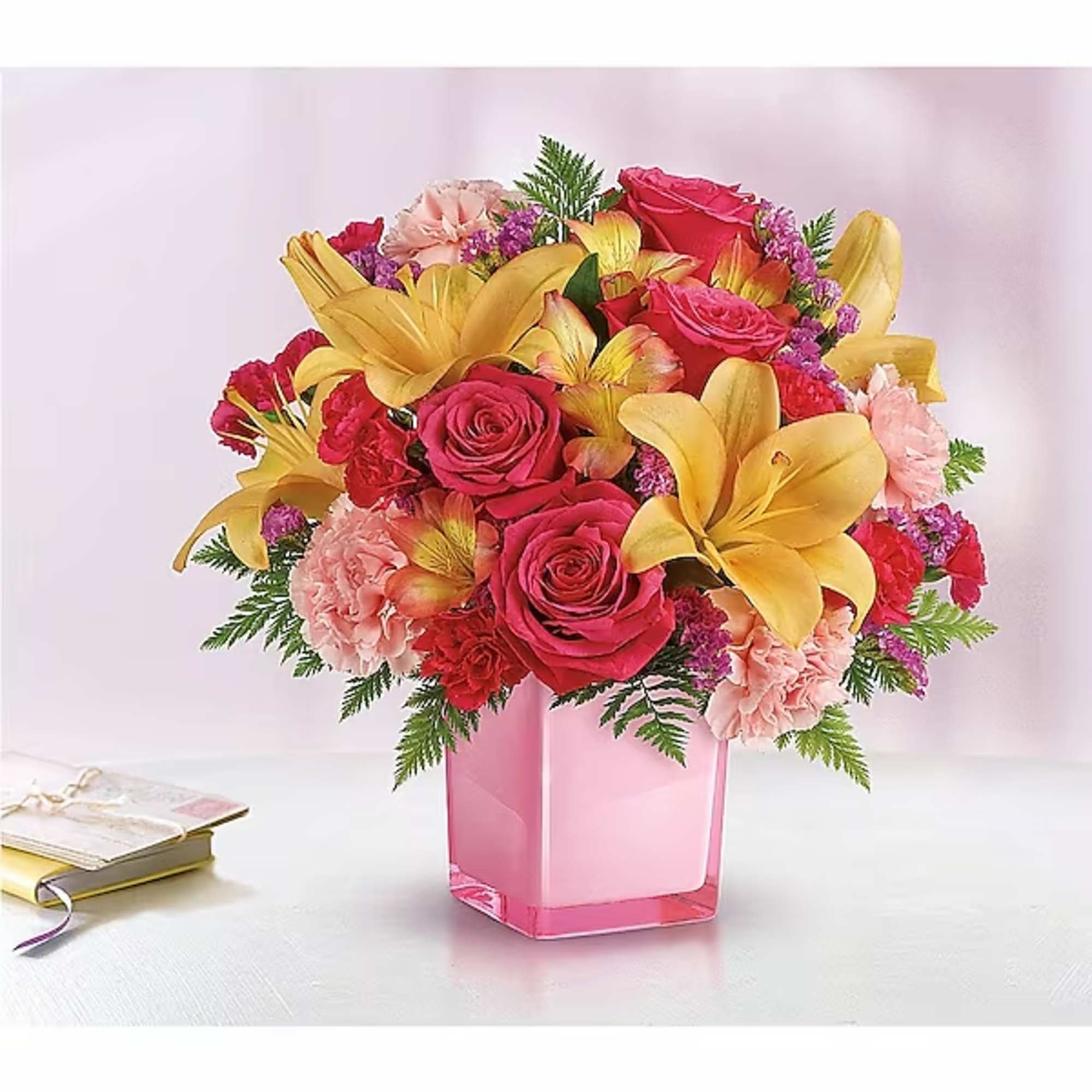 Bouquet of pink roses, yellow lilies, and carnations in a pink vase