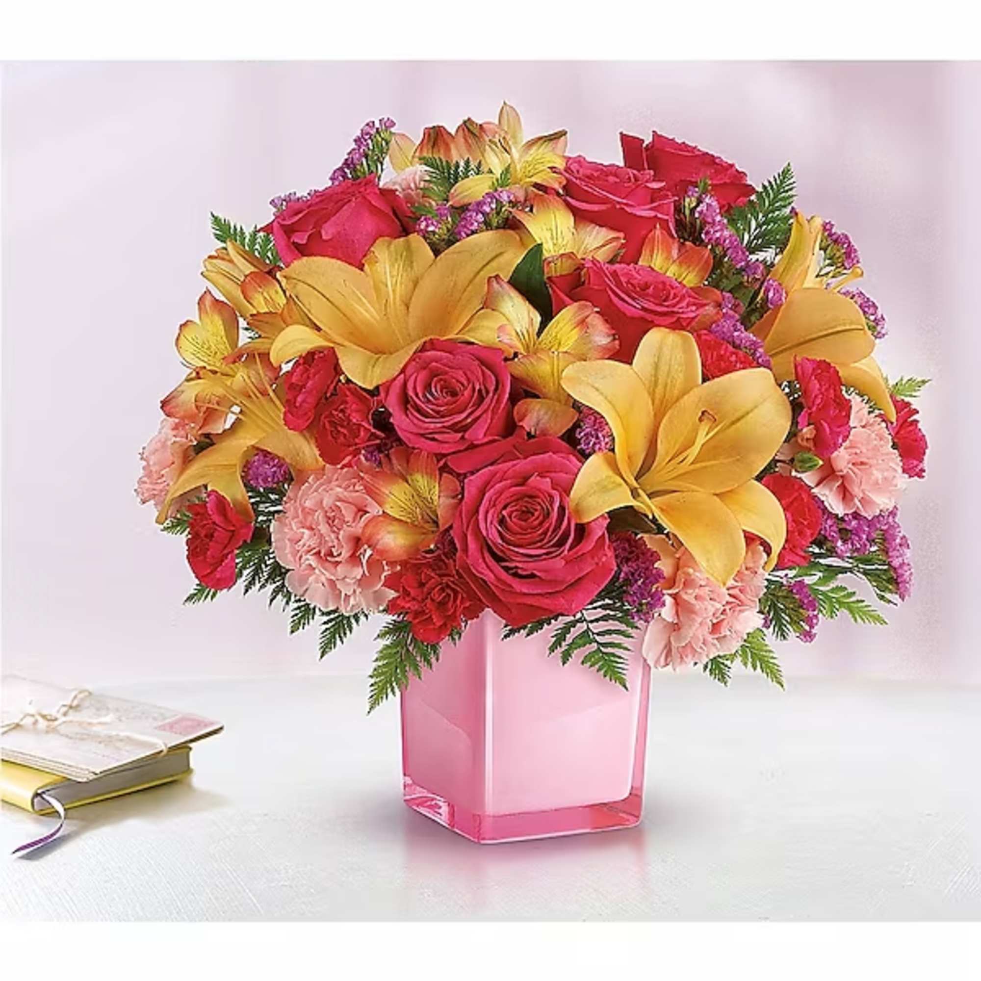 Bouquet of pink roses and yellow lilies in a pink glass vase