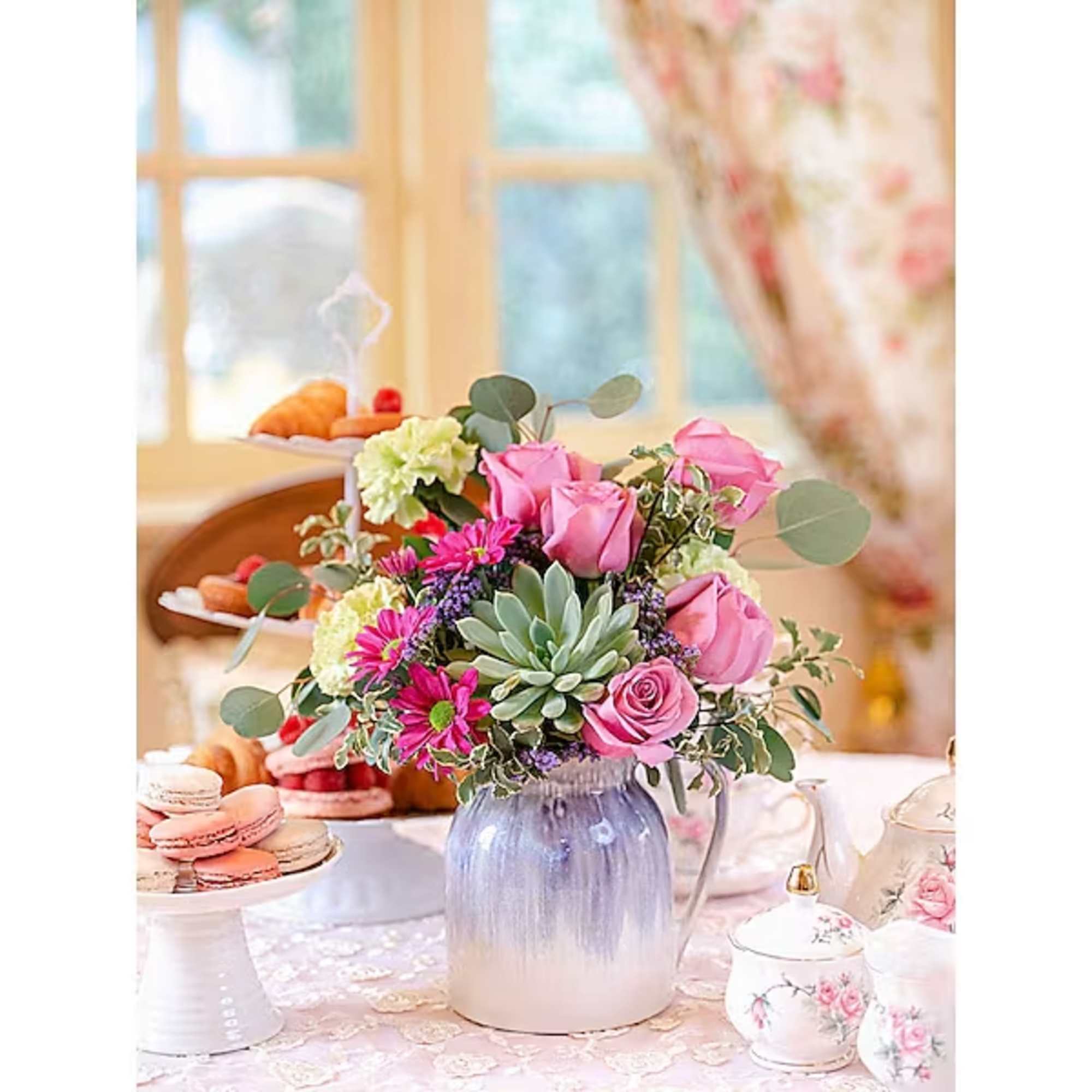 Pink roses and mixed flowers in a blue vase on a dessert table