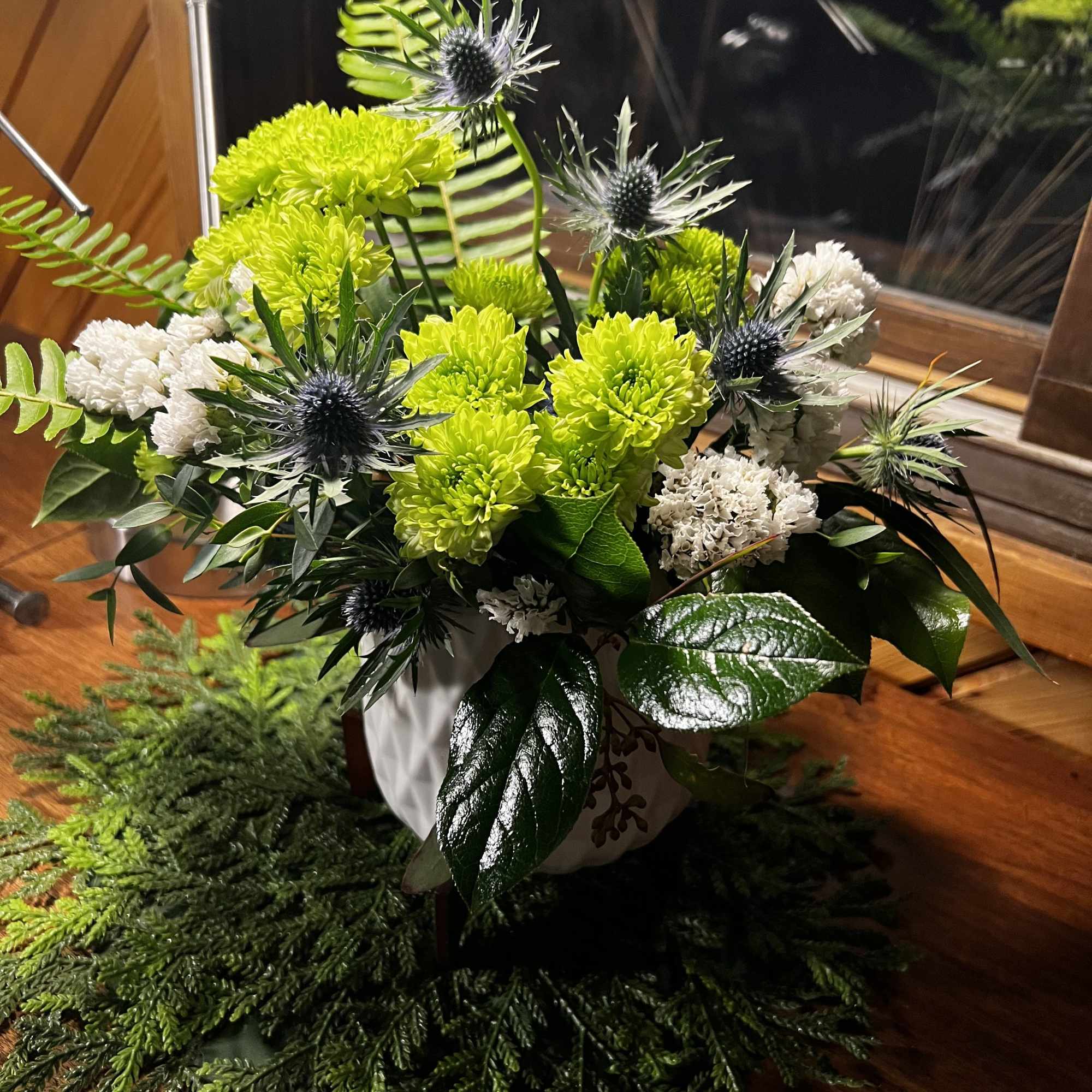 Green and white floral arrangement in a white vase
