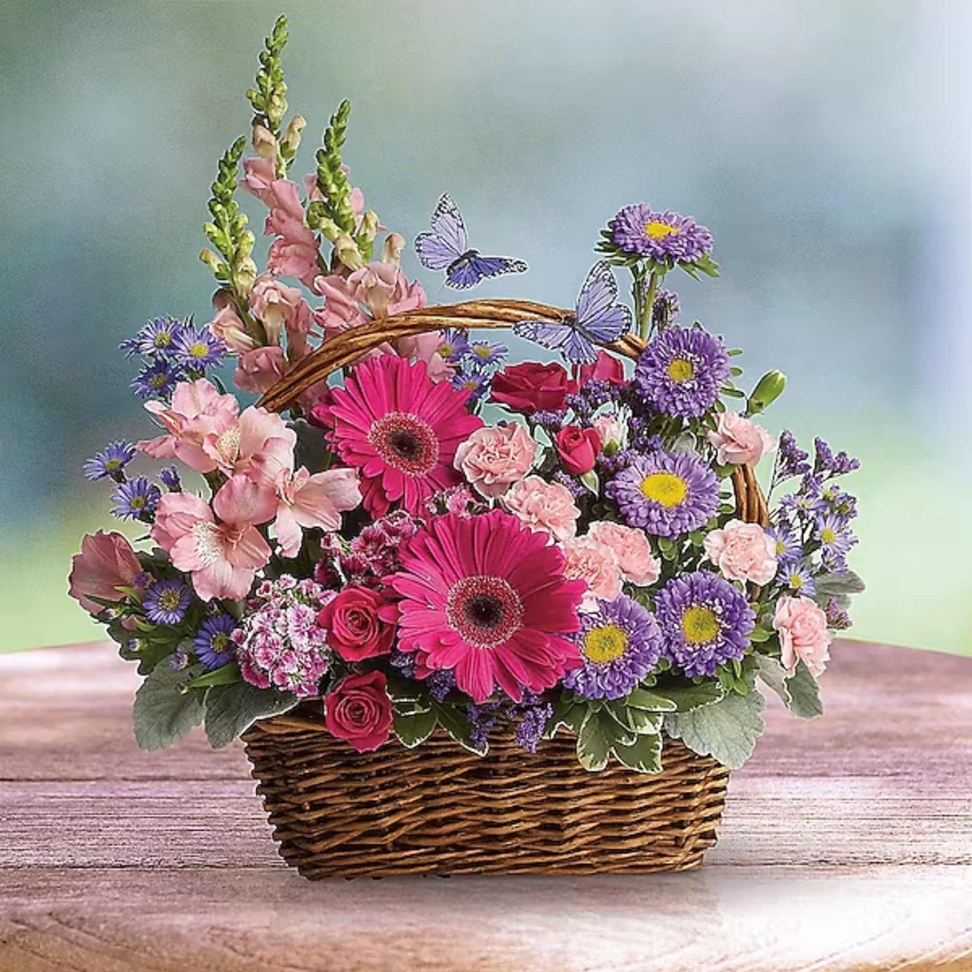 Basket arrangement of pink and purple flowers with butterflies