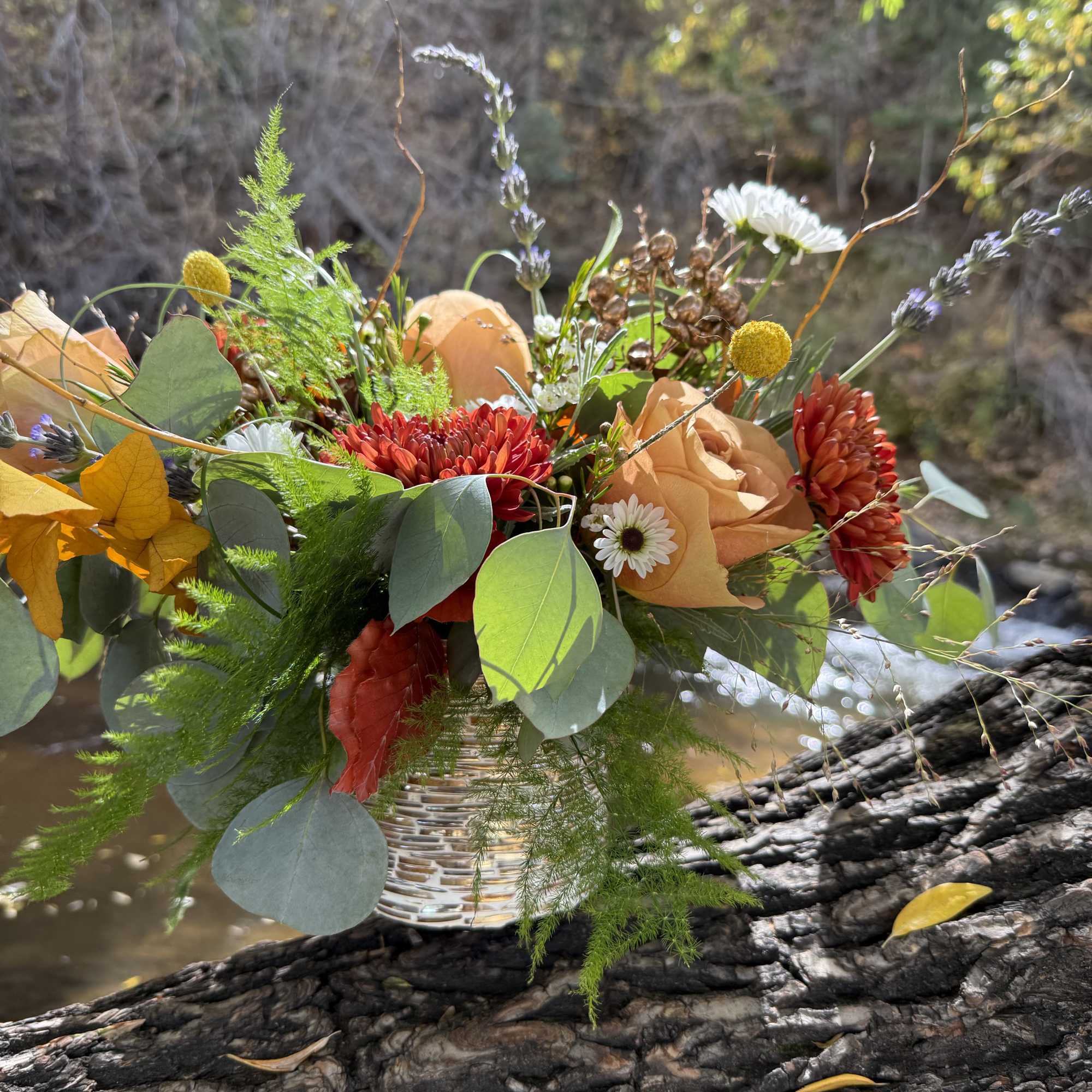 Mixed bouquet in a woven vase with peach, red, and white flowers