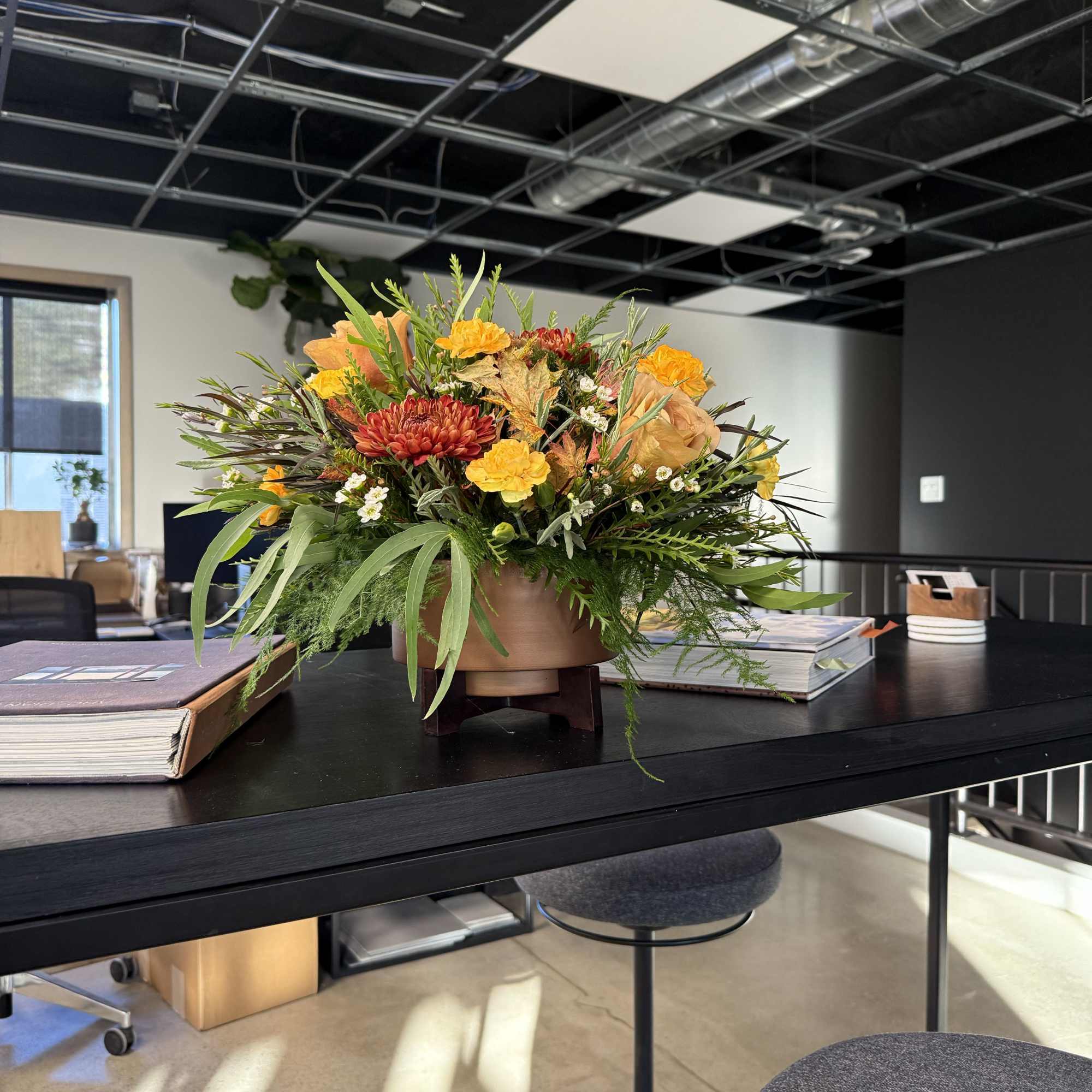 Low floral centerpiece with orange and yellow blooms in a round vase