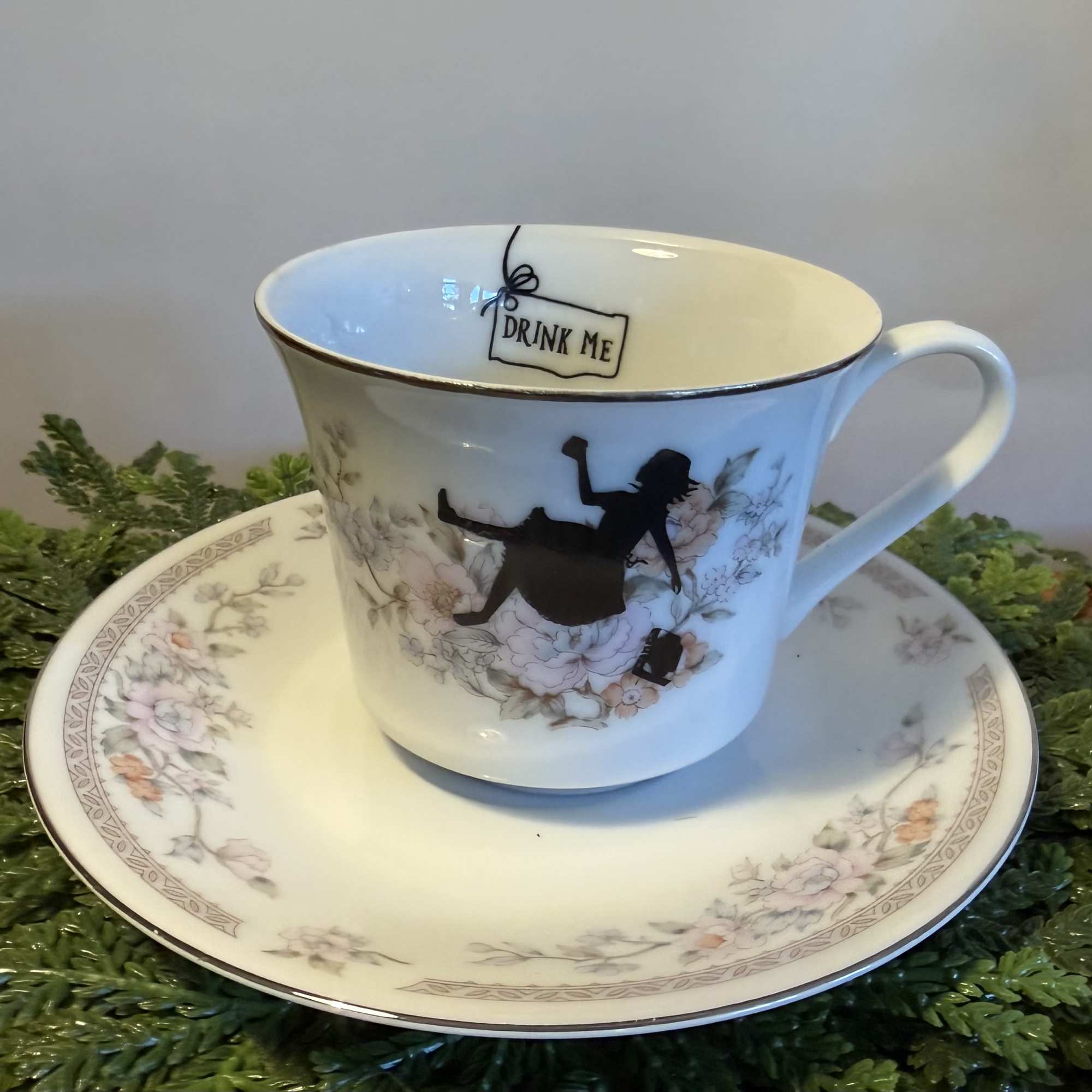 Decorative teacup and saucer with floral pattern and a Drink Me tag