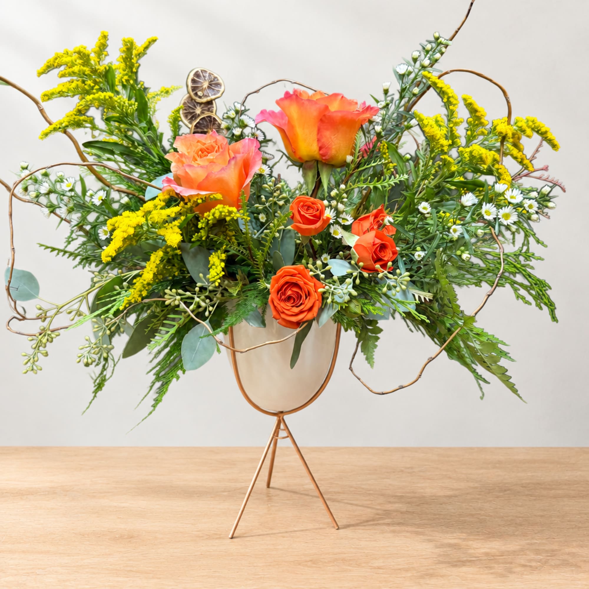 Orange roses and yellow filler flowers in a metal stand vase