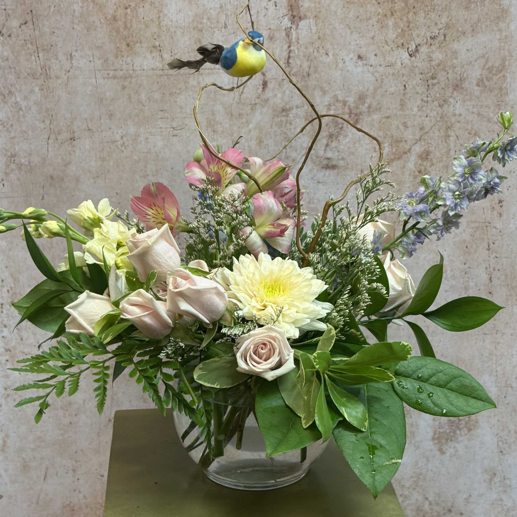 Mixed bouquet in a clear glass vase with pale roses and a yellow bloom