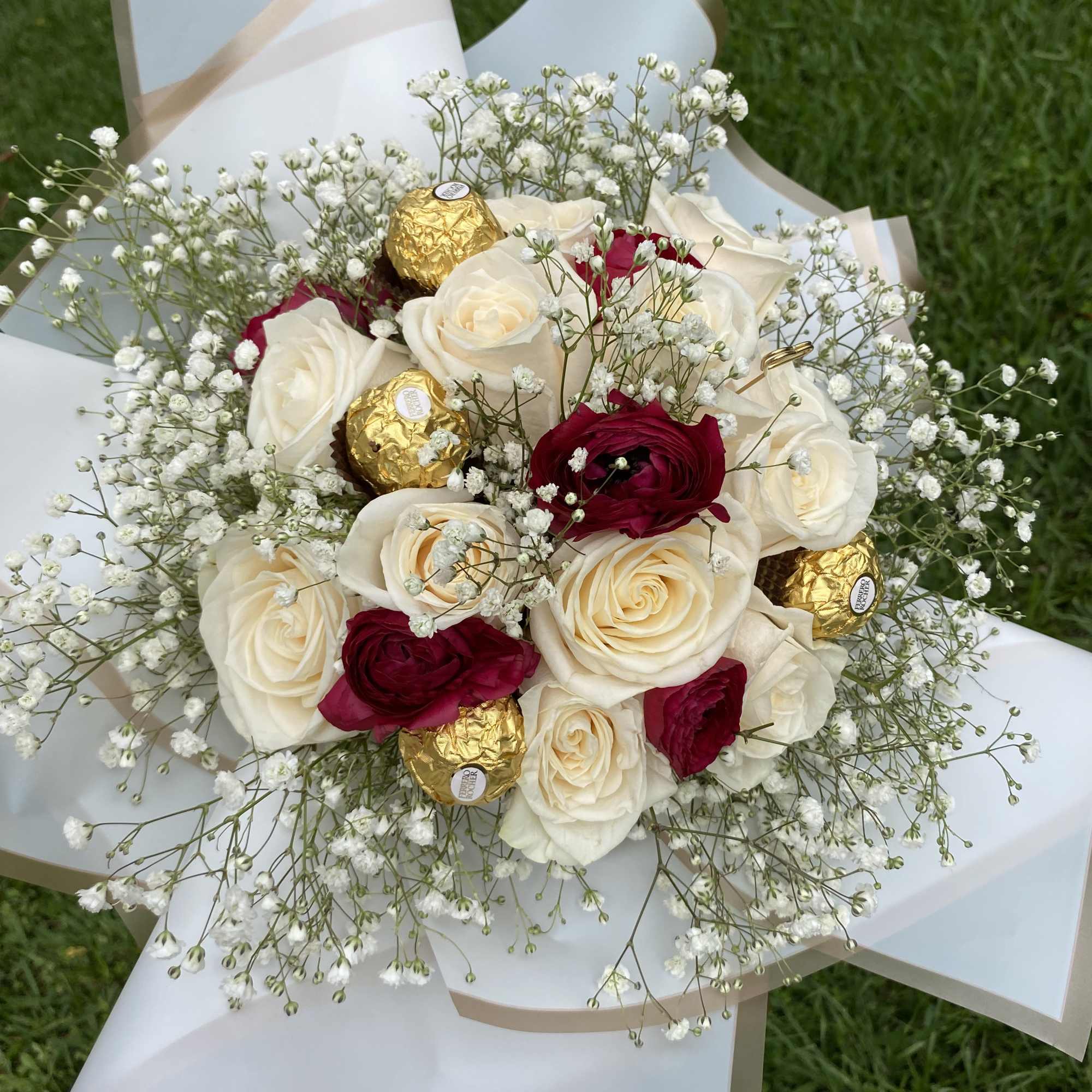 Bouquet of white and red roses with baby’s breath and gold-wrapped chocolates