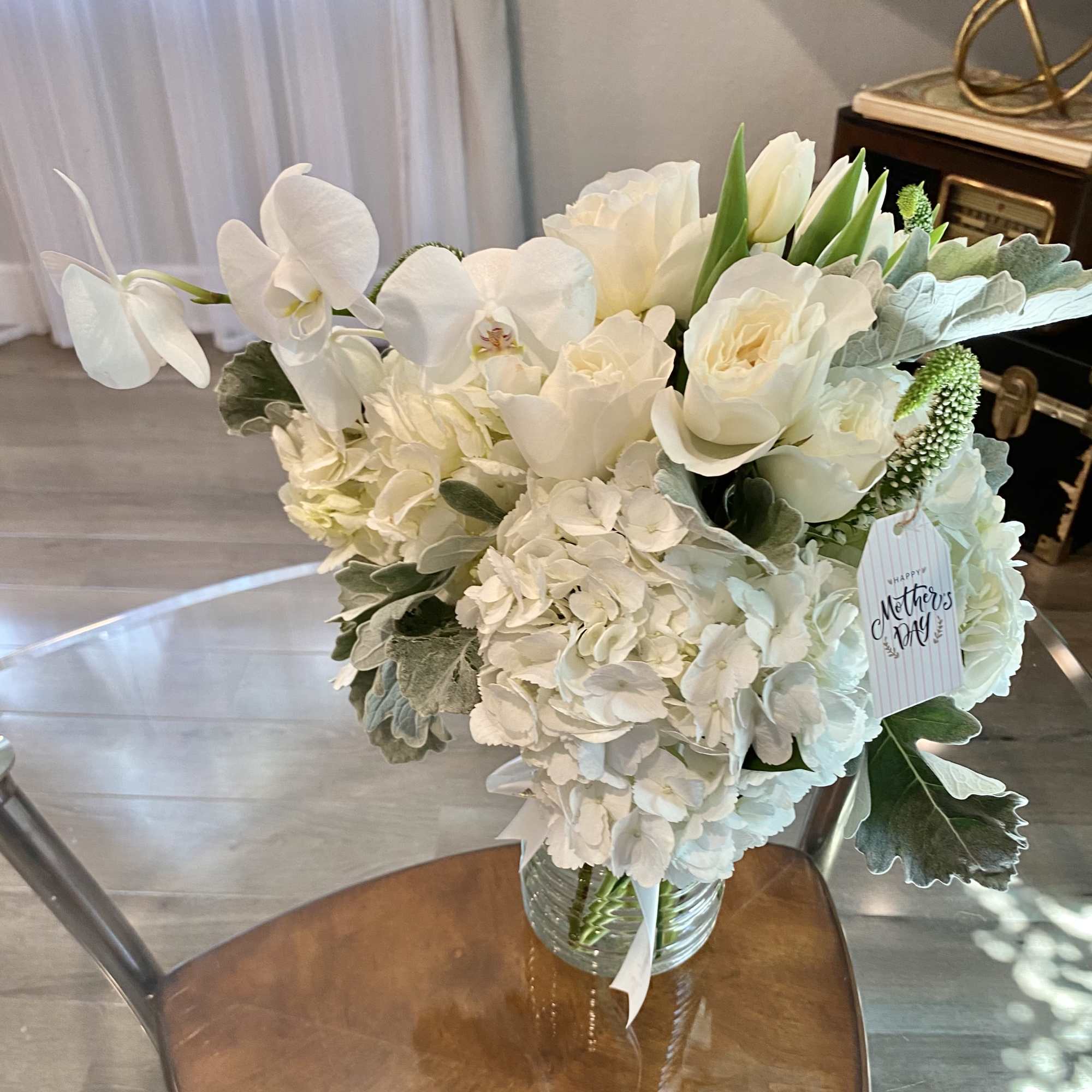 White floral bouquet in a glass vase with a Mother's Day tag