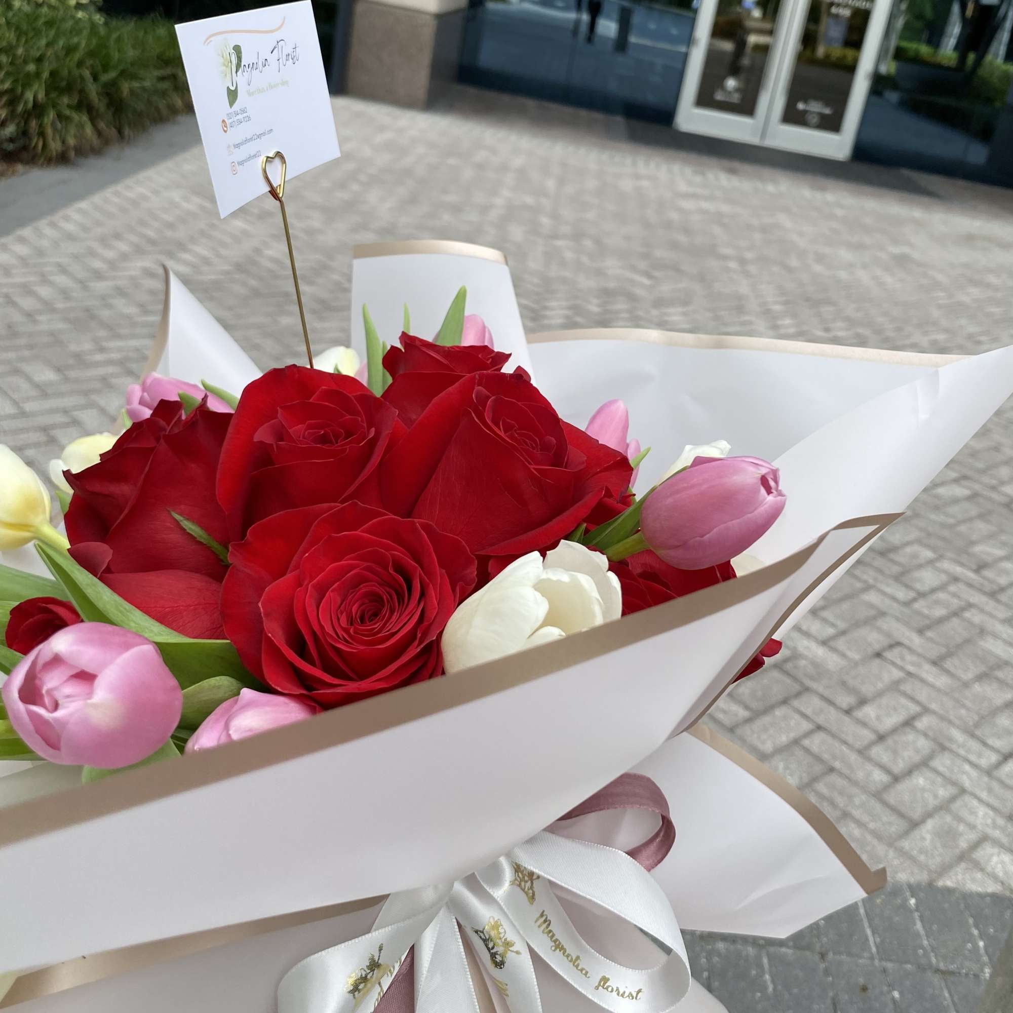 Bouquet of red roses and pink tulips wrapped in white paper