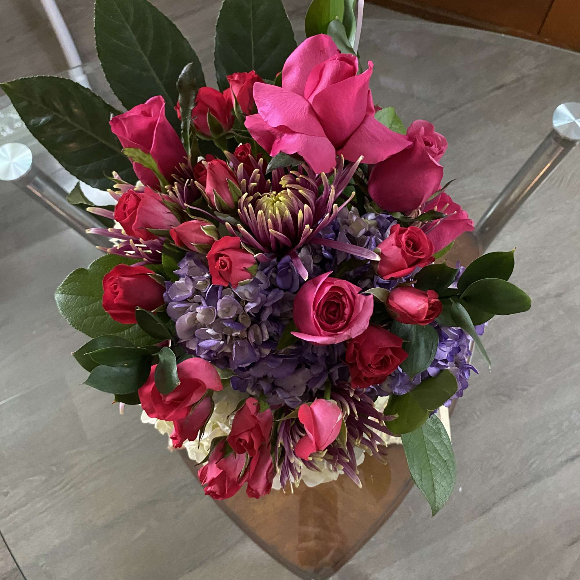 Bouquet of pink roses and purple flowers with large green leaves