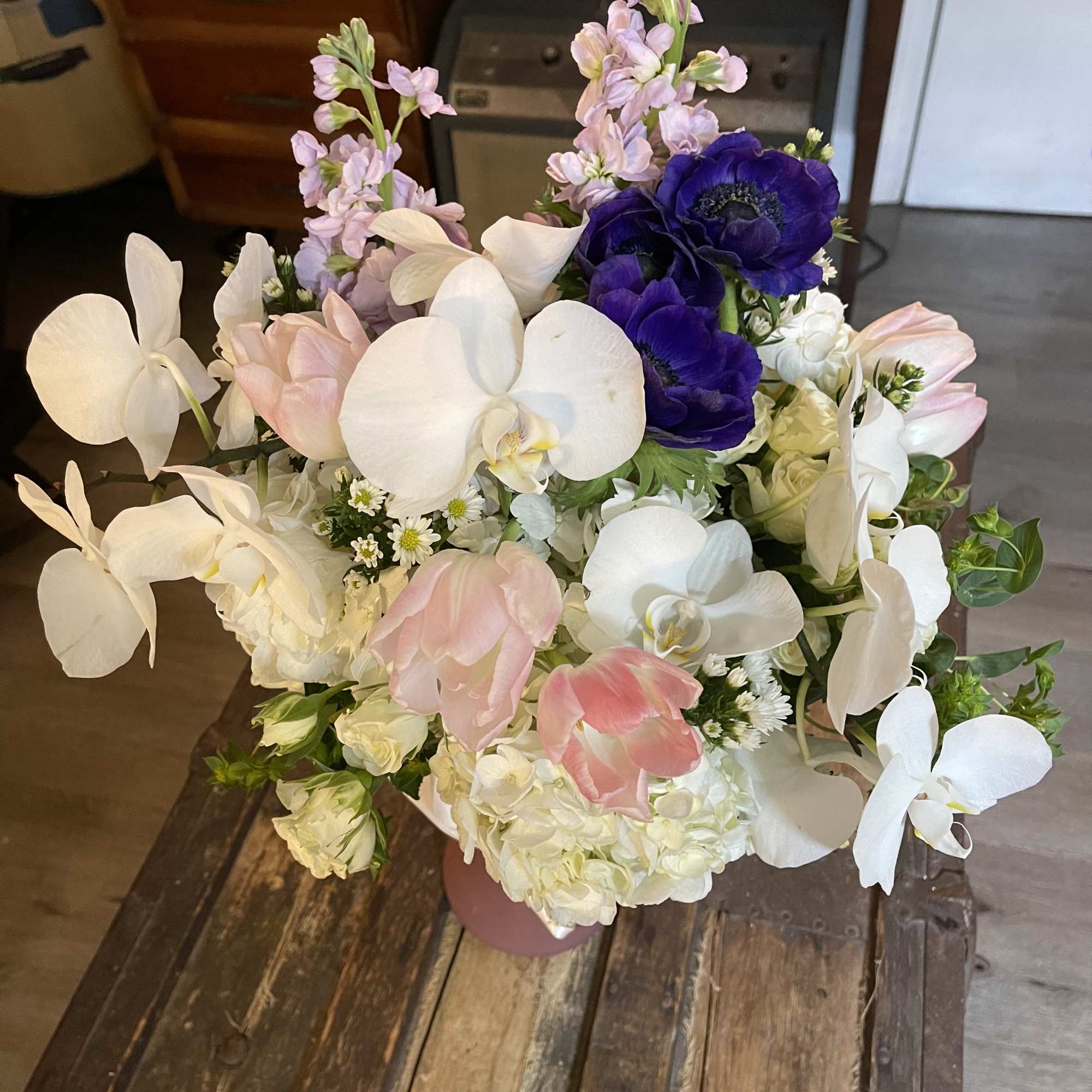 Bouquet of white orchids, pink tulips, and purple anemones in a vase